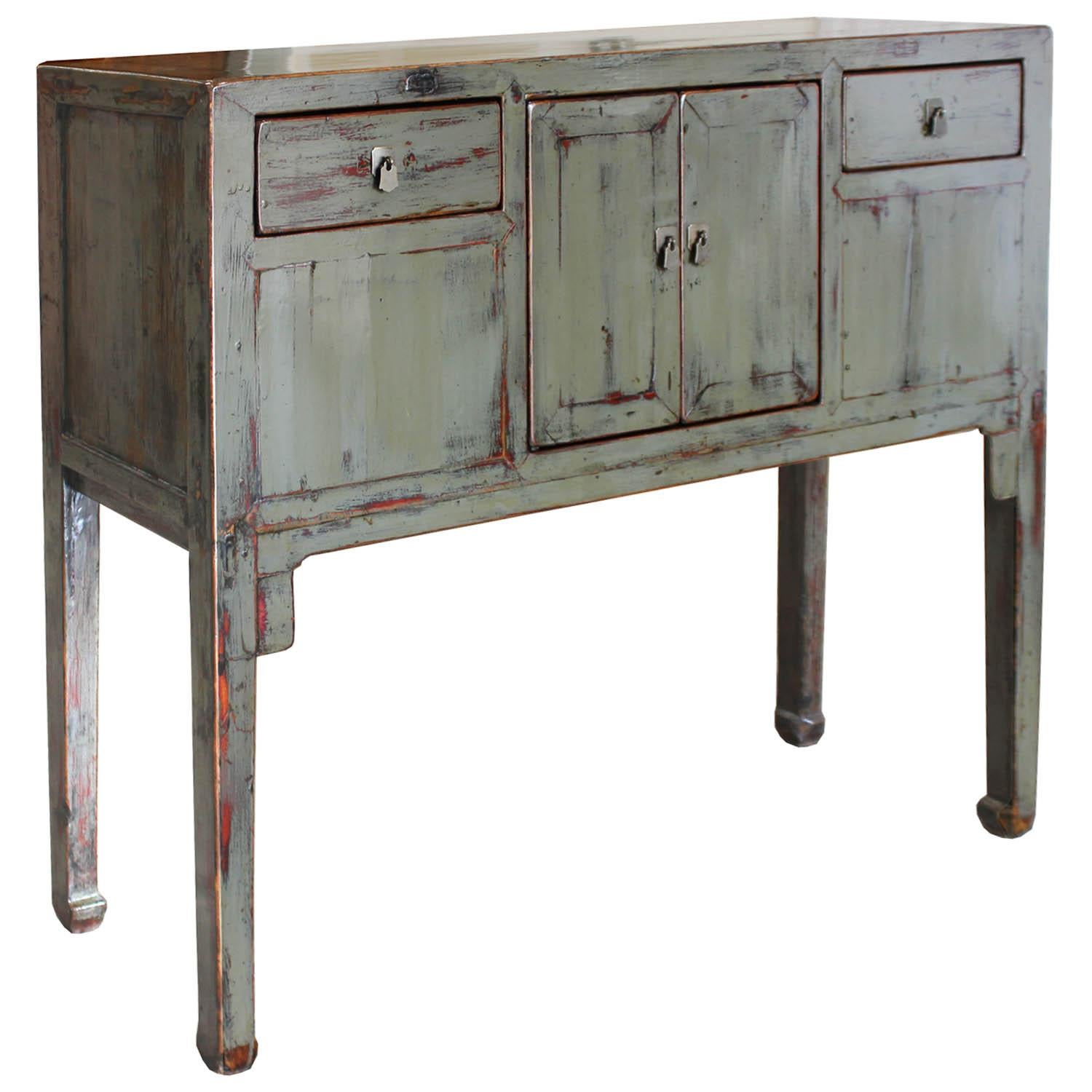 Gray lacquer buffet with clean lines and exposed wood edges features subtle distressing, red under-tone, high legs and horse hoof-style feet. Place in an entry way and place keys and other accessories in the drawers. New hardware.
 