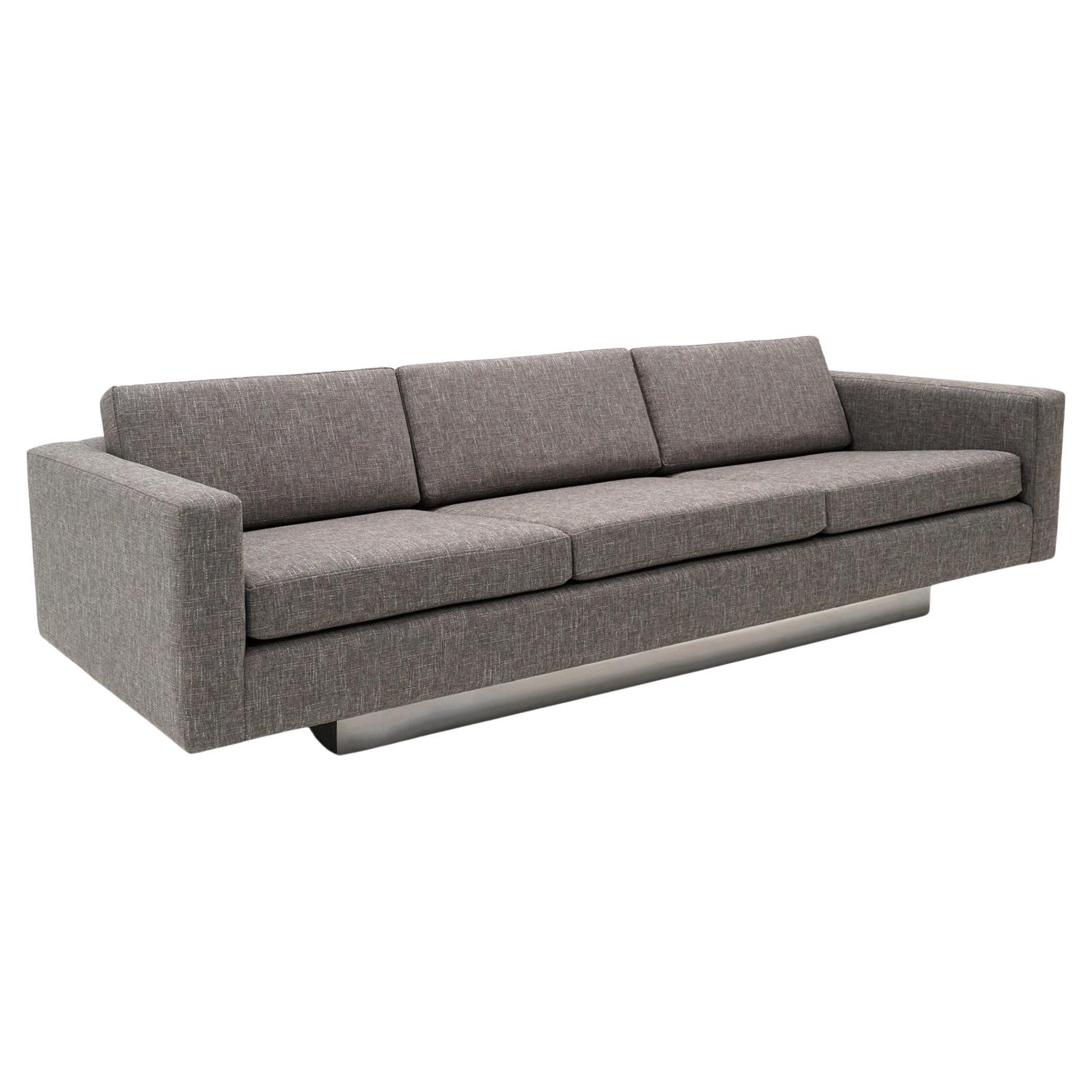 Expertly reupholstered three seat medium grey sofa with arms attributed to Harvey Probber. Also similar to designs by Milo Baughman. Very high quality construction, heavy, and very comfortable. The sofa floats on a solid wood base clad in chromed