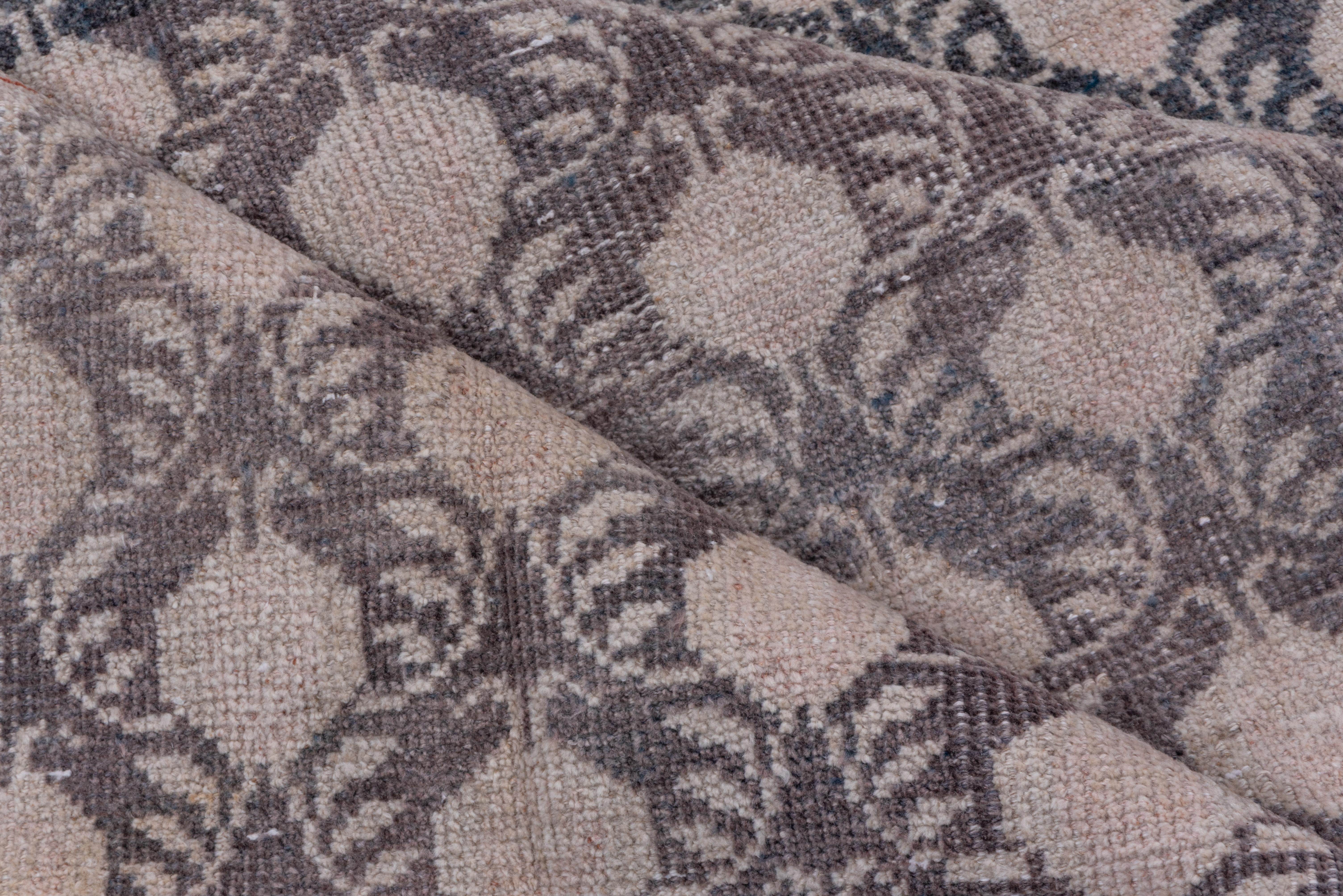 This rustic Anatolian large scatter shows a vertically offset, columnar simplified flower design on a bluish-mauve ground, framed by a tonally en suite plain border. Textile pattern.
 