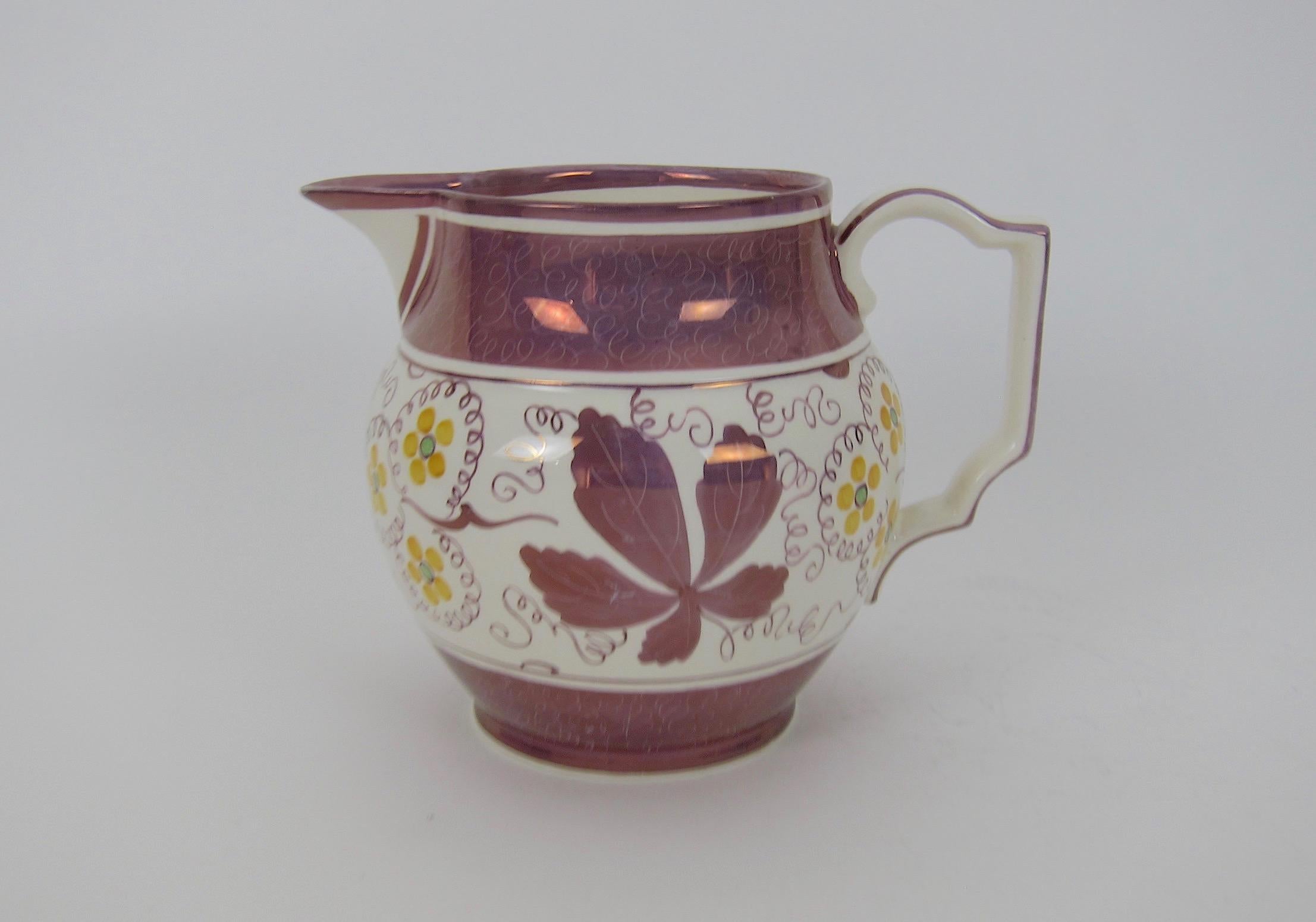 A vintage earthenware pitcher or jug decorated with a hand painted pink metallic lustre glaze from Gray's Pottery at Stoke-on-Trent, England. Although created between 1933 and 1945, the pitcher's ivory ground is decorated in the style of antique