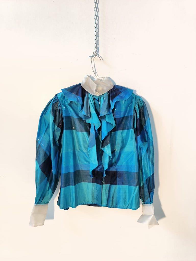 This rare vintage blouse by Milanese designer Grazia Fava dates back to the late 1970s or early 1980s and is a perfect example of elegant Italian craftsmanship.
Made of 100% pure silk, it features a bold striped pattern in turquoise, teal, and navy