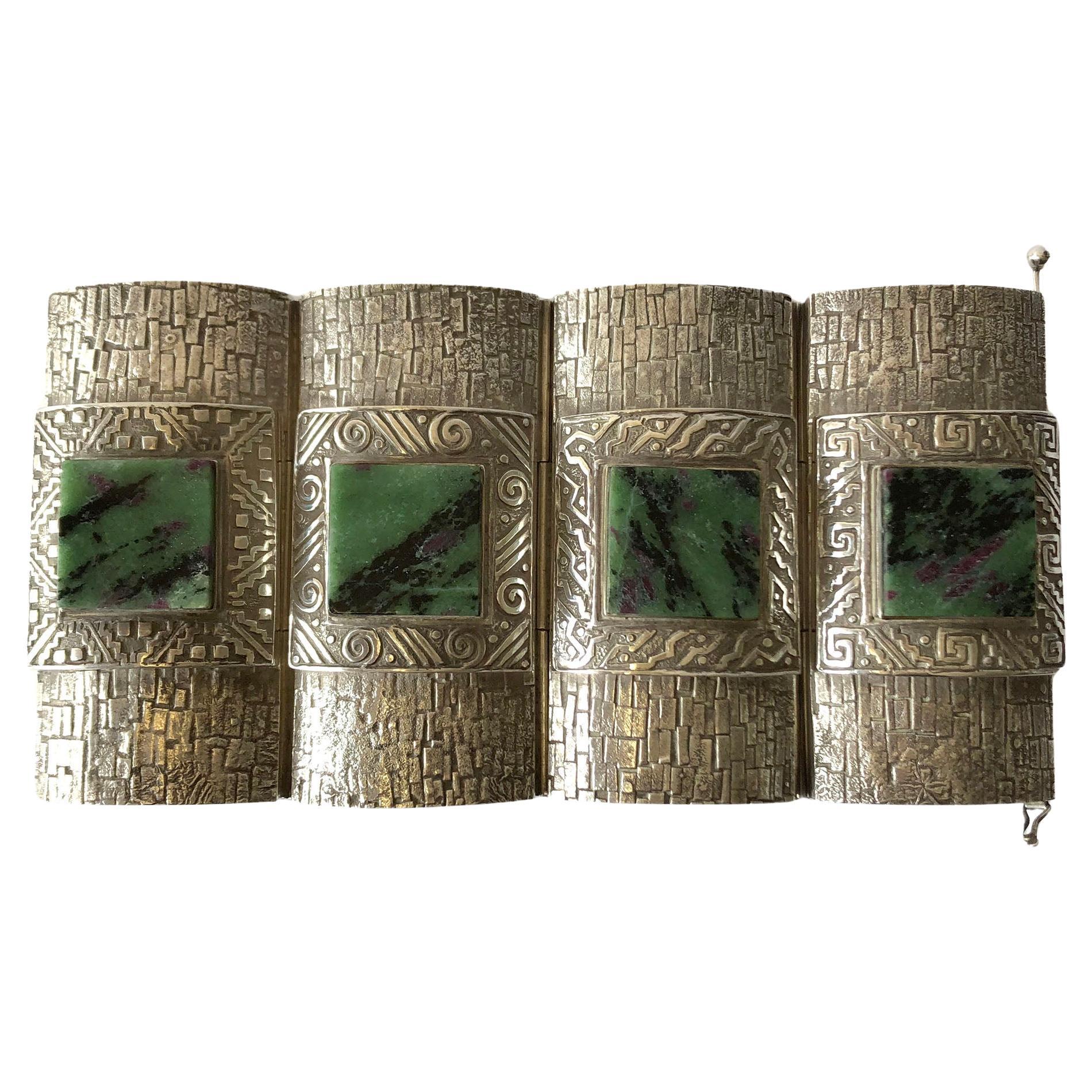 Important bracelet manchette moderne aztèque péruvien en argent sterling et quartz vert par Graziella Laffi circa 1965.  Le bracelet se compose de quatre panneaux d'argent sterling gravé, chacun présentant un motif différent du suivant et contenant