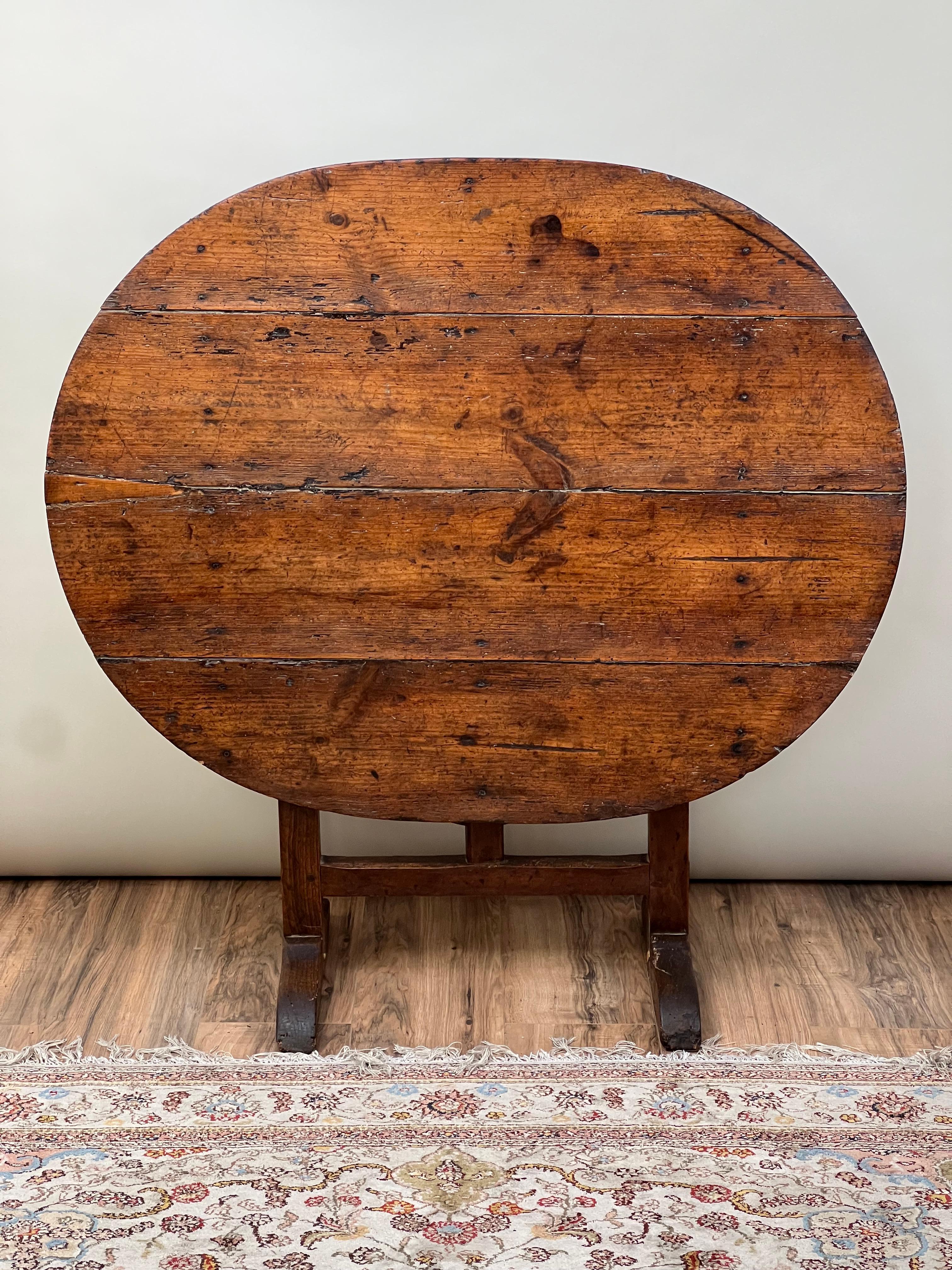 This 18th-century French wine table is a testament to enduring craftsmanship and a storied past. Its robust wooden top, worn by time and use, narrates the table’s history, not only through its rich patina but also through an old repair that adds