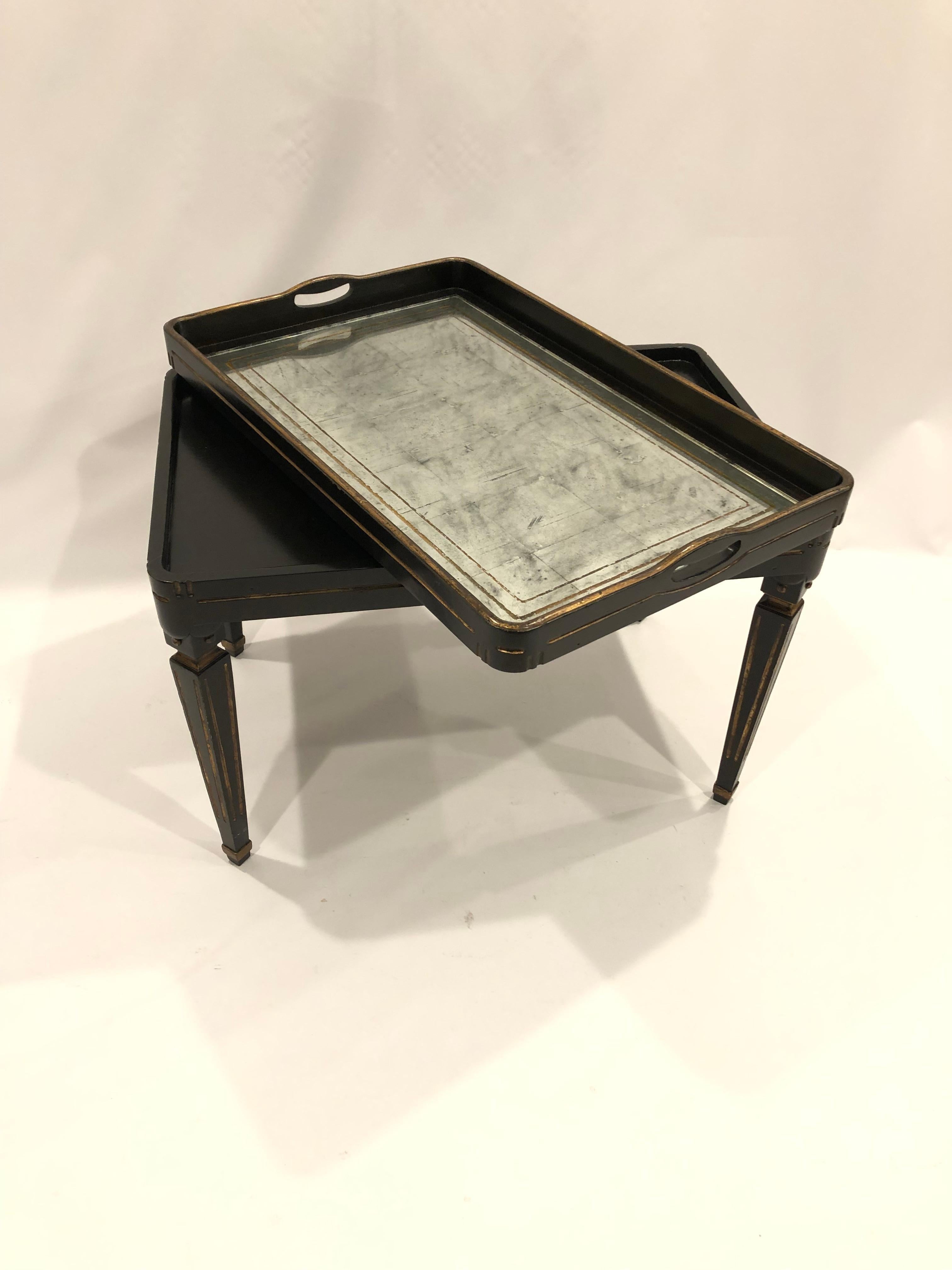 A handsome small rectangular coffee table having removeable tray top with inset aged mirror having gold outline around the periphery. Base and gallery of the table are ebonized to make a glamorous contrast to the eglomise top. Legs are equally