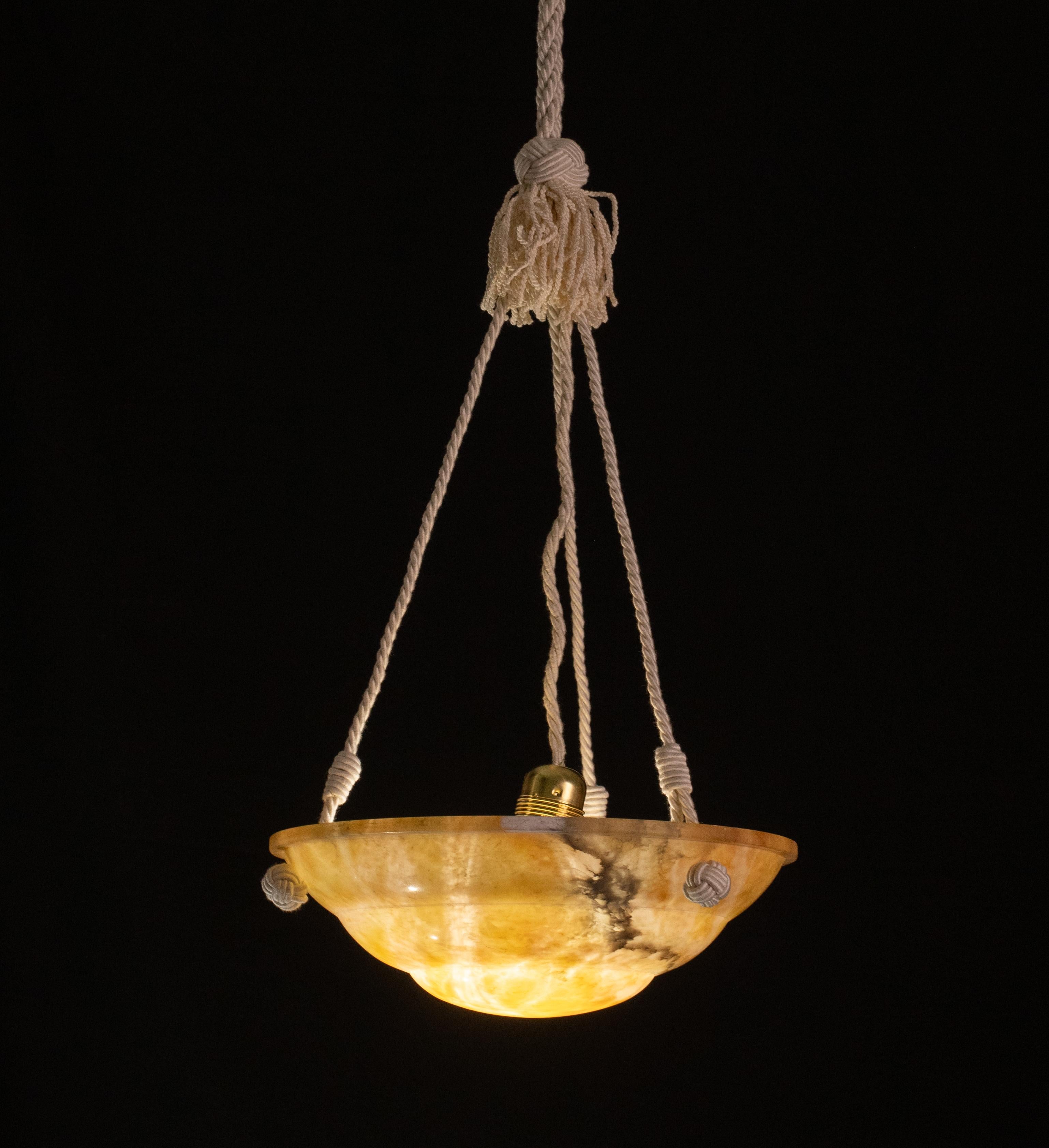 Orange alabaster chandelier. Period circa 1940. The chandelier is 85 centimetres high, the diameter measures 30 centimetres. 
The stone is completely original, the three rope cord has been replaced is new, can be shortened or lengthened on request.