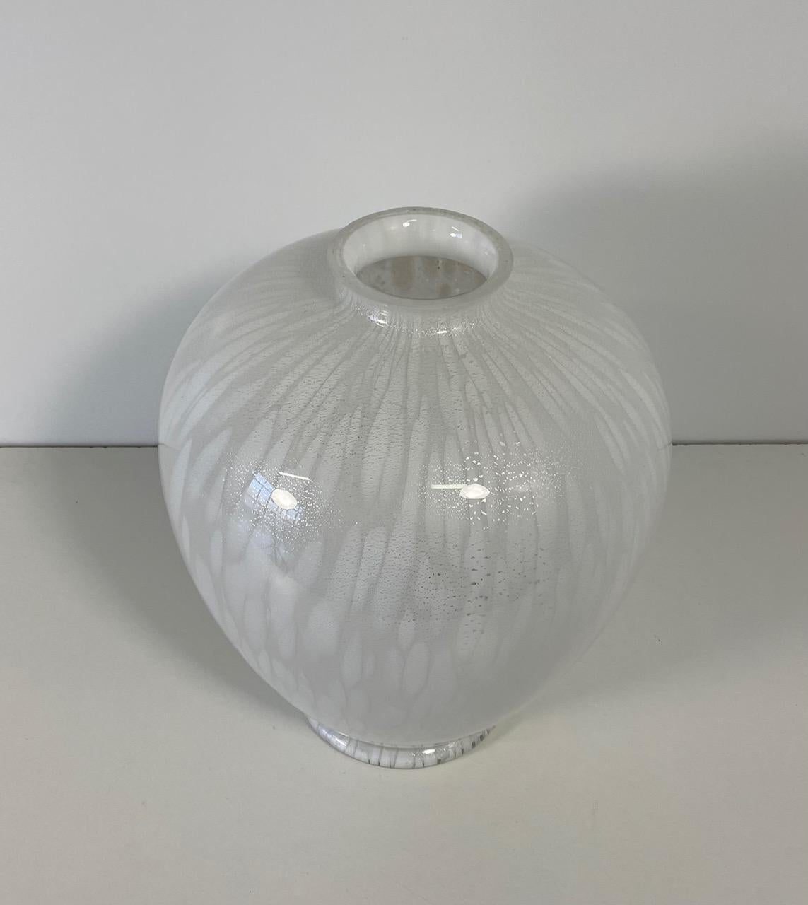 This elegant vase was produced in Murano, Venice (Italy) by master glass artists. 

The vase features different shades of white created using particular glass processing techniques and numerous silver inclusions.
 