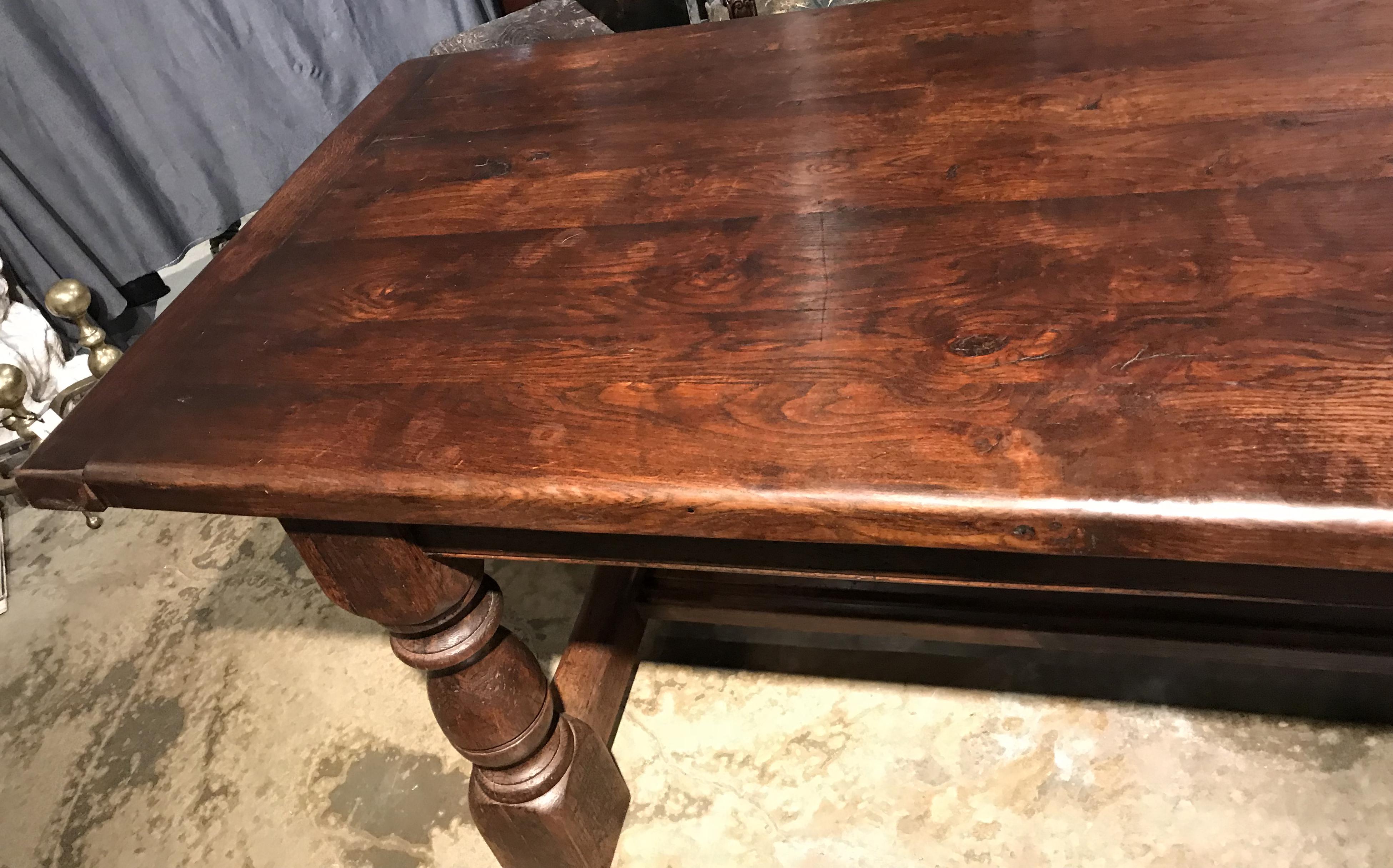 A great oak Jacobean style two part refectory table with solid heavy rectangular top with traditional peg and cleat ends surmounting a sturdy frame with six turned baluster legs with thick cross stretchers between each set and two center stretchers