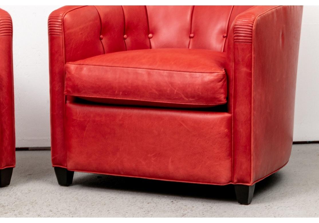 Pair of very well made Club Chairs in a Brilliant Lipstick Red Leather with button tufted backs and insides of the sloping arms. With bands of stitched details on the crest rails and arm ends. The deep skirts raised on dark stained square tapering