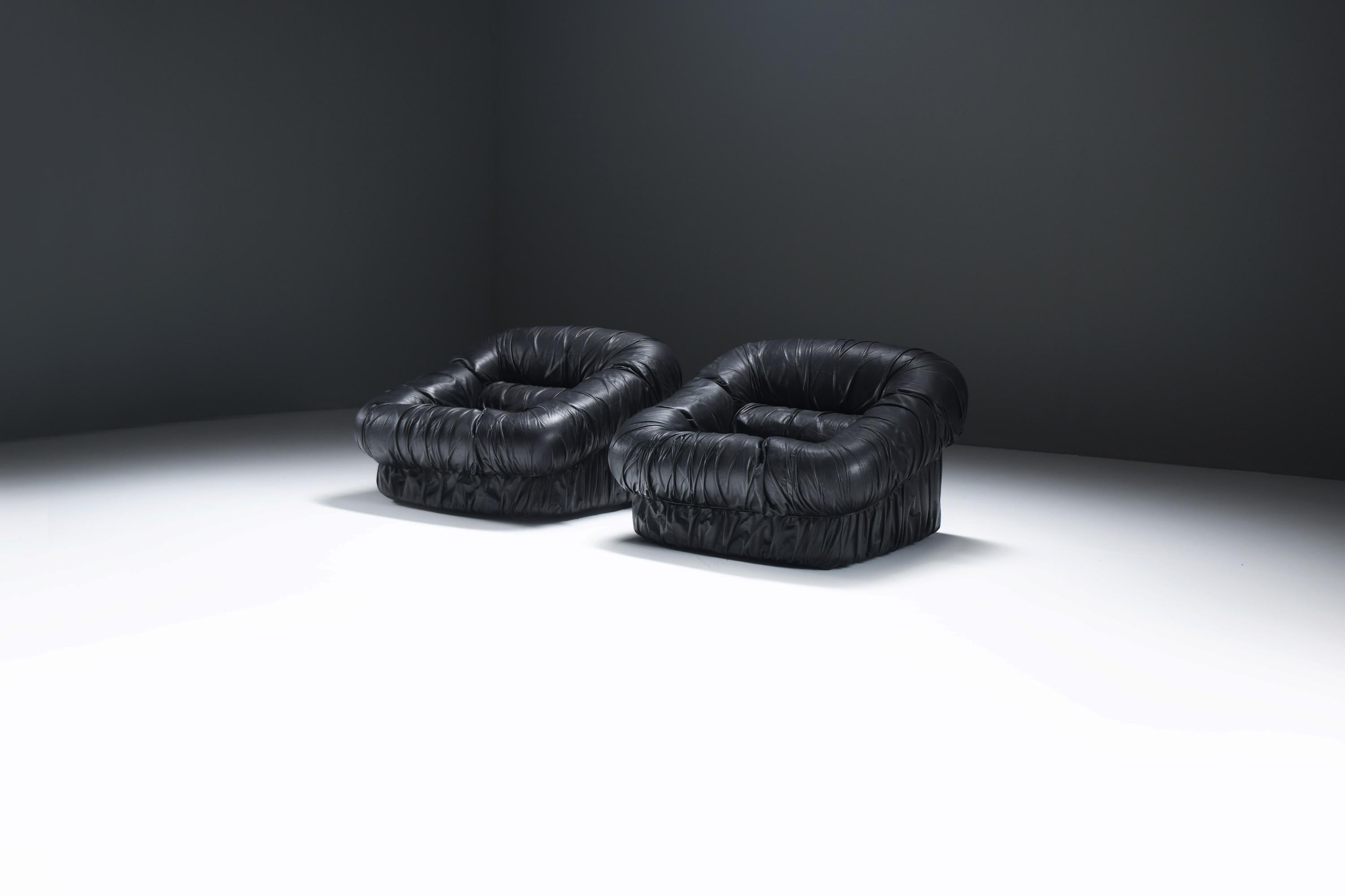 This vintage set of Italian leather lounge chairs is in pristine condition, showcasing the timeless appeal of their original black leather upholstery. The matching pair exudes an air of refined elegance, perfectly complementing any classic or