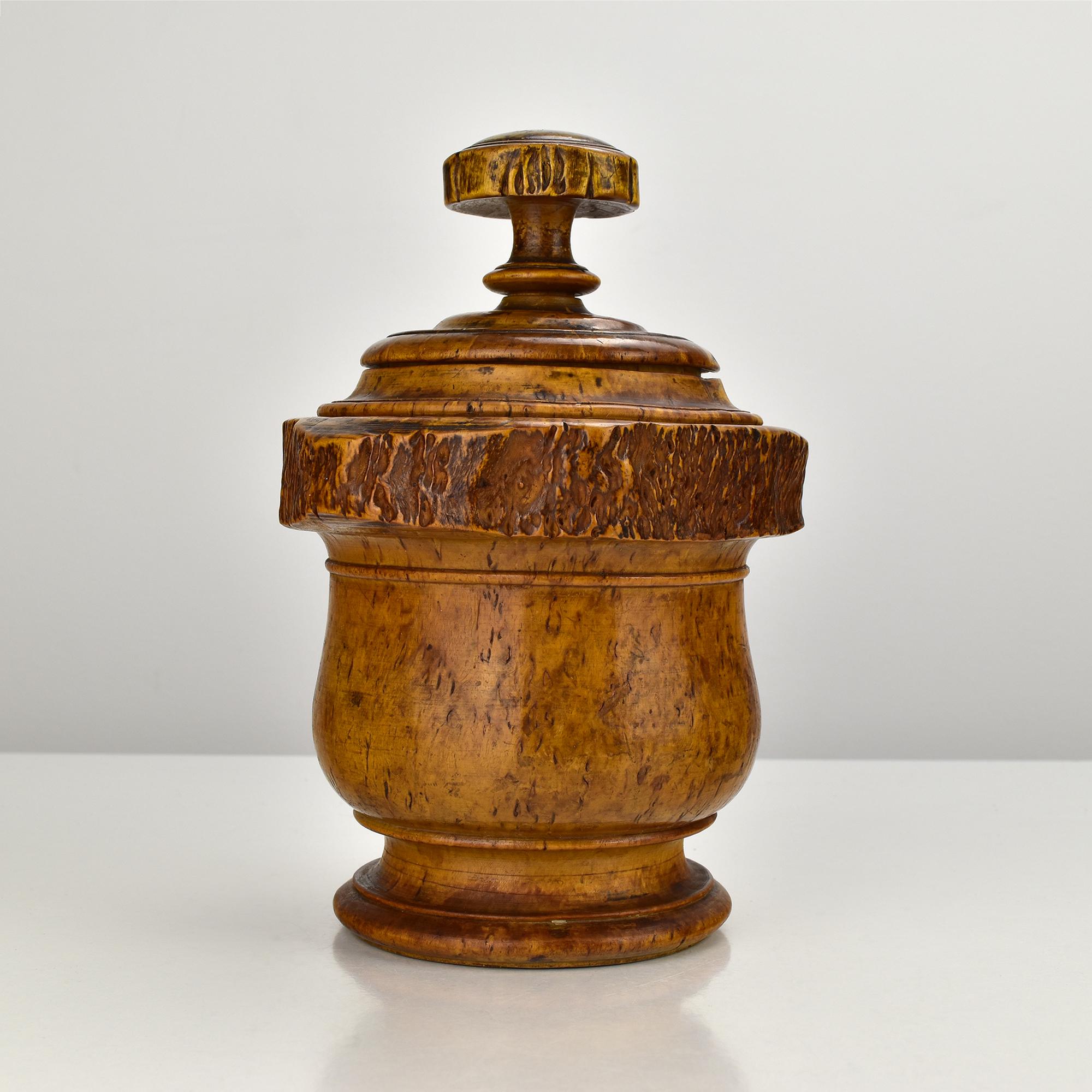 This beautifully hand-turned burl wood tobacco jar is a striking piece of Mid-Century Modern craftsmanship, signed by artist R. Kaeser. The jar features a domed lid with a rounded finial and a wide, textured burl band that showcases the natural