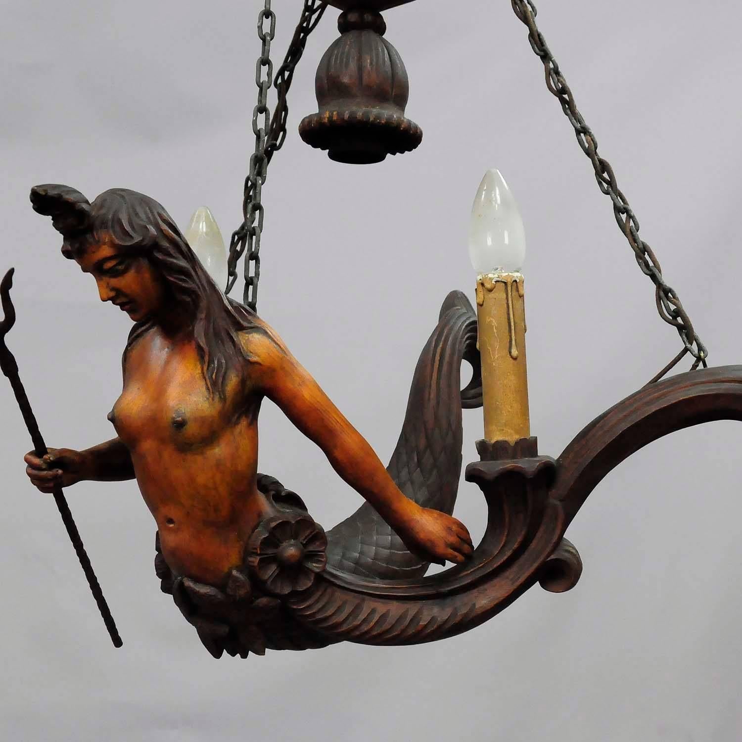 This extra-ordinary lusterweibchen is made completely from wood without any antlers. A hand-carved and hand-painted statue of a beautiful mermaid with a trident in the right hand. Executed circa 1910. The chandelier is equipped with two