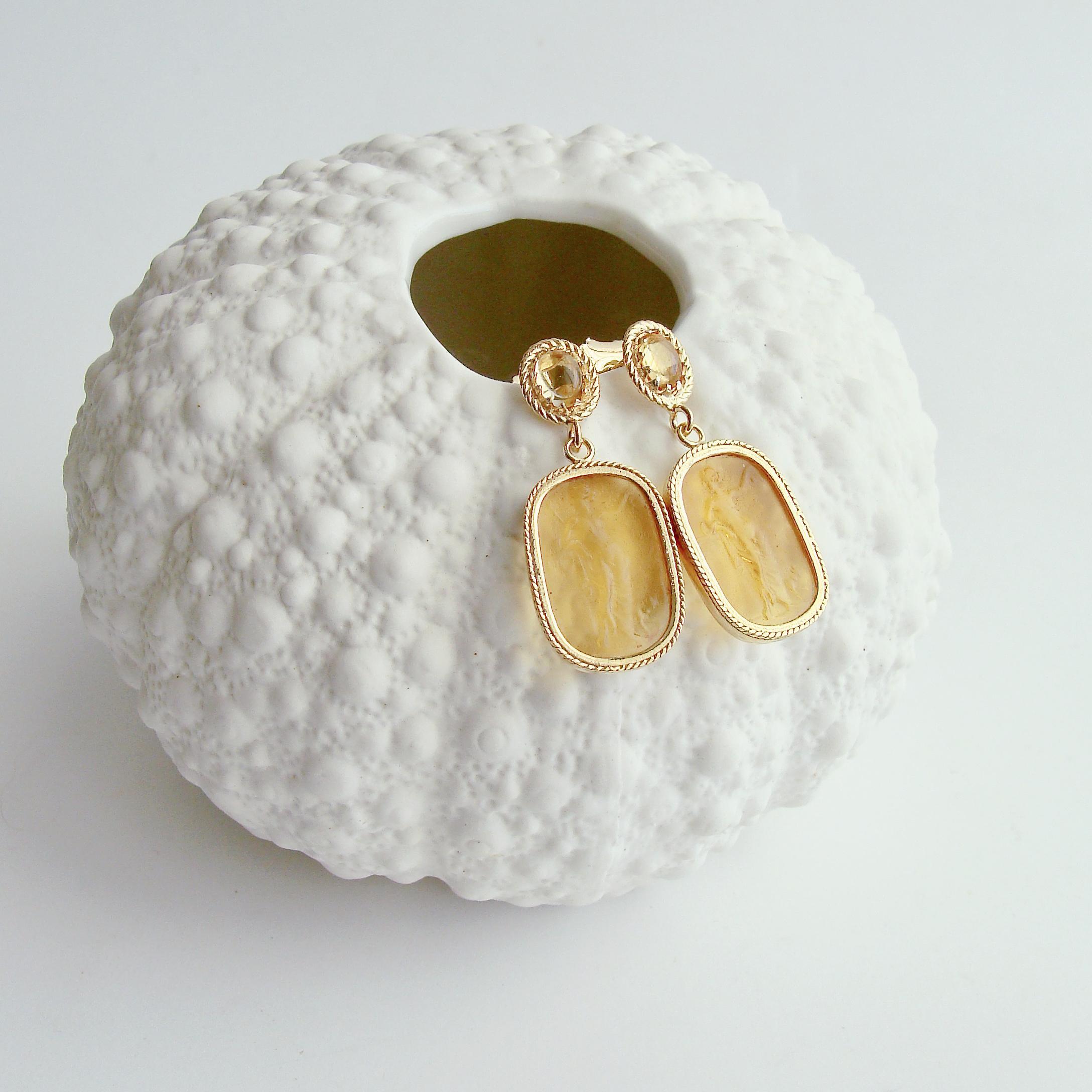 A stunning pair of Grecian goddess  intaglios with gossamer drape  in a gorgeous citrine color, are the nexus of these remarkable post style earrings.  The venetian glass intaglios are encased in a delicate herringbone setting which dangle sweetly