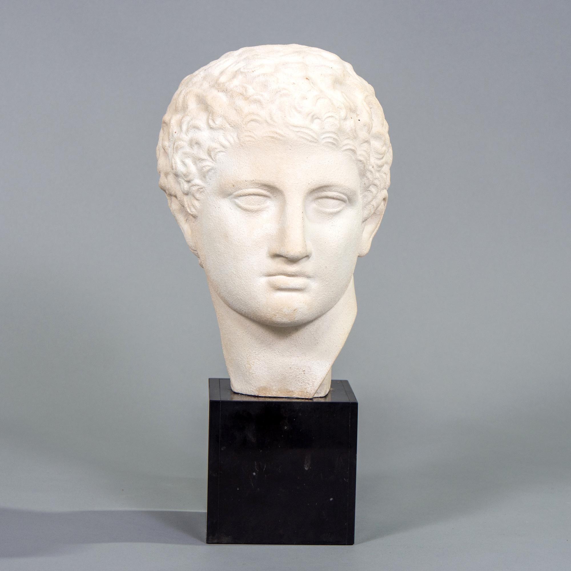 Found in England, this circa 1960s plaster bust in the Grecian tradition is mounted on a black marble base. Unknown maker.