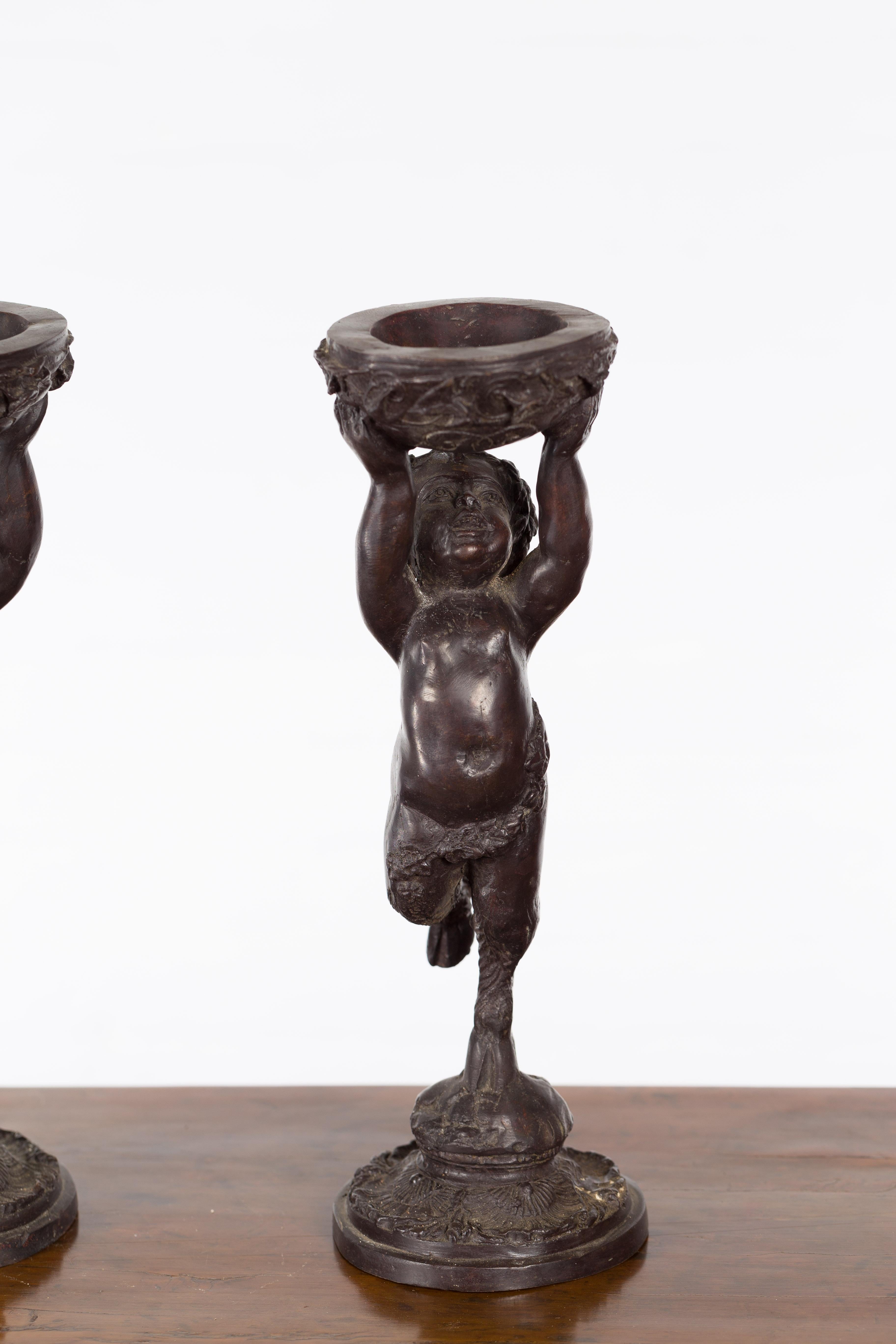 Greco-Roman Style Bronze Candle Holders Depicting Young Satyrs Holding Vessels In Good Condition For Sale In Yonkers, NY