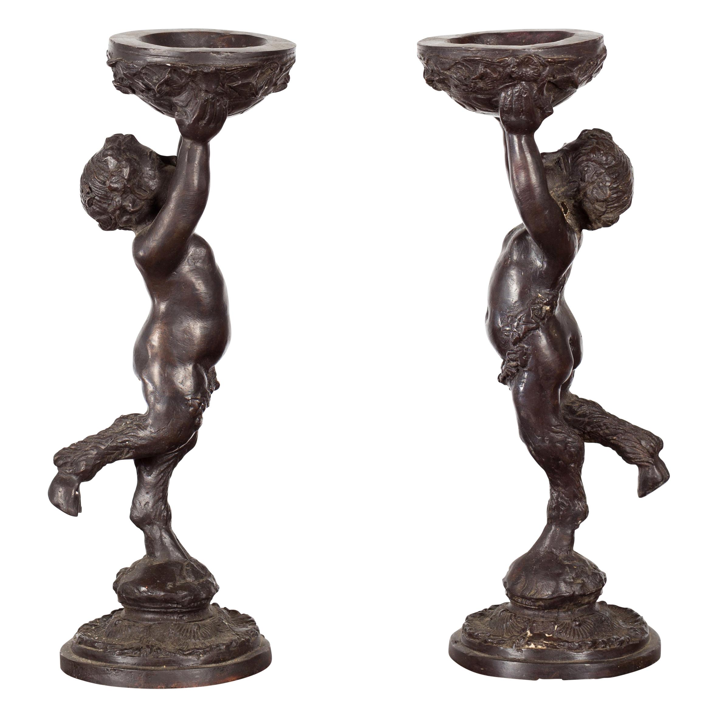 Greco-Roman Style Bronze Candle Holders Depicting Young Satyrs Holding Vessels For Sale