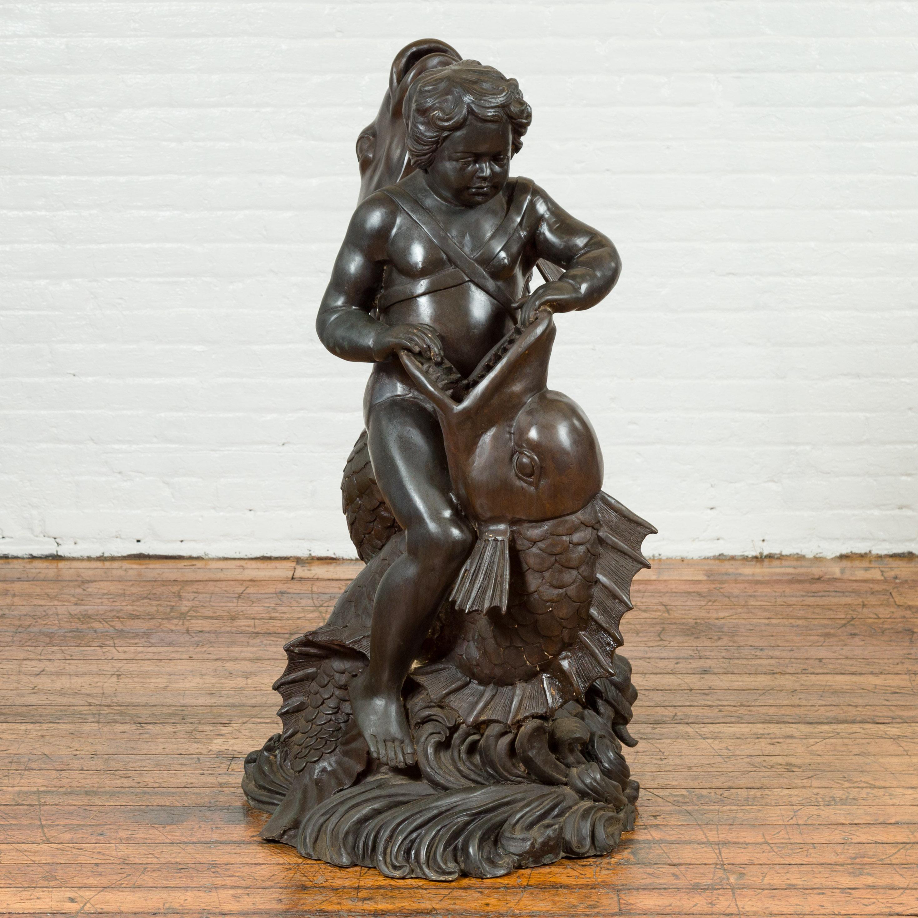 A Greco-Roman inspired vintage bronze fountain from the mid 20th century, depicting a putto riding a dolphin. Created with the traditional technique of the lost-wax (à la cire perdue) that allows a great precision and finesse in the details, this