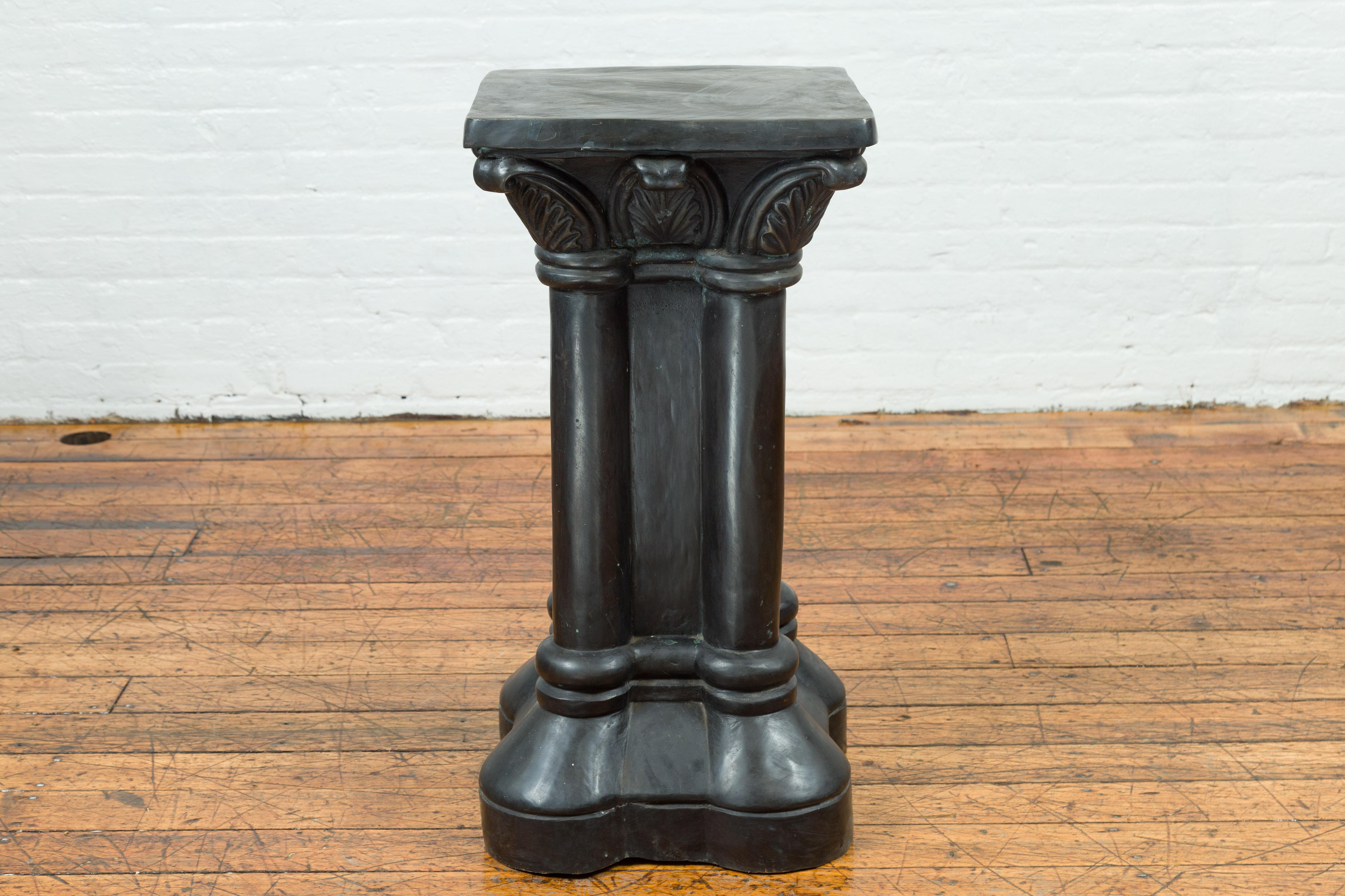 A vintage Greco-Roman style bronze pedestal base from the mid-20th century, with square top, palmette motifs and quadrilobe base. Charming us with its unusual presence and Greco-Roman inspired design, this pedestal base features a square top resting