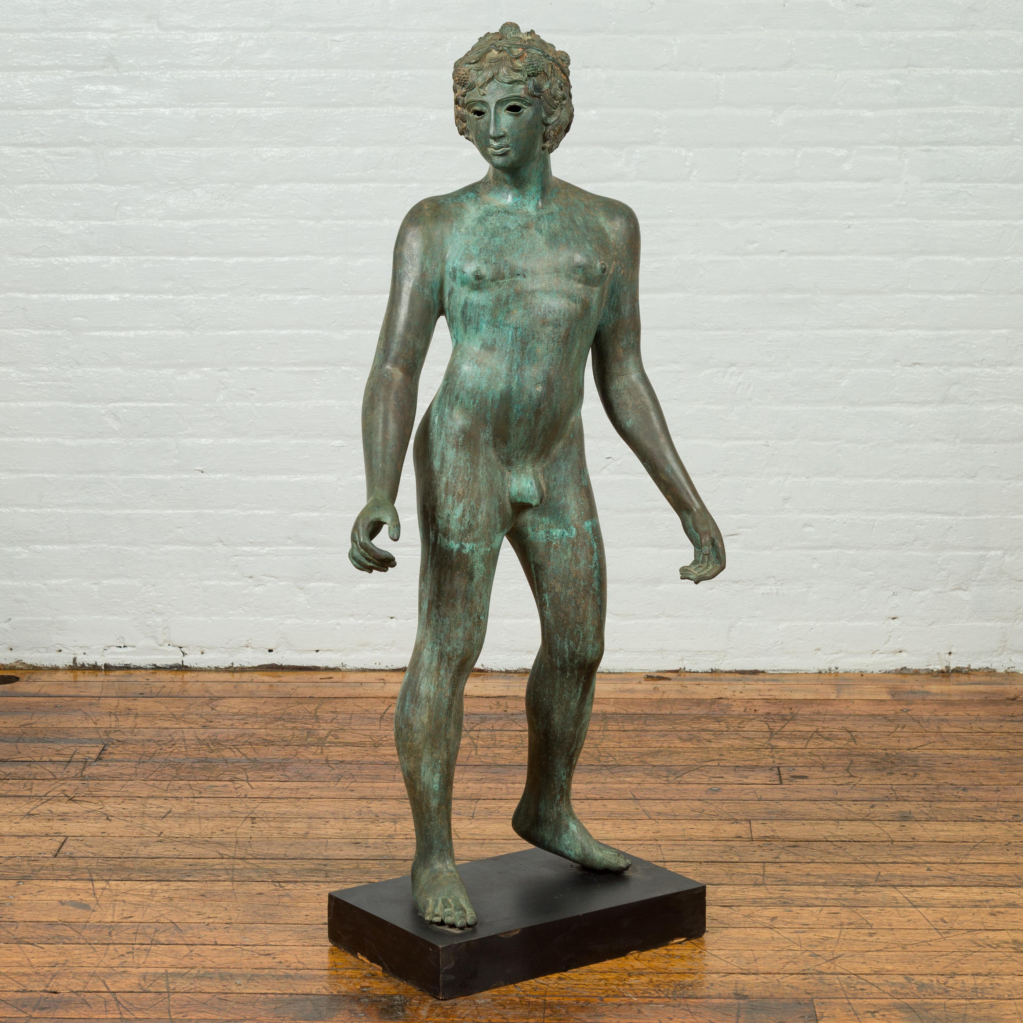 A vintage Greco-Roman style bronze nude statue from the 20th century with verde patina and wooden pedestal base. Created with the traditional technique of the lost-wax (à la cire perdue) that allows a great precision and finesse in the details, this