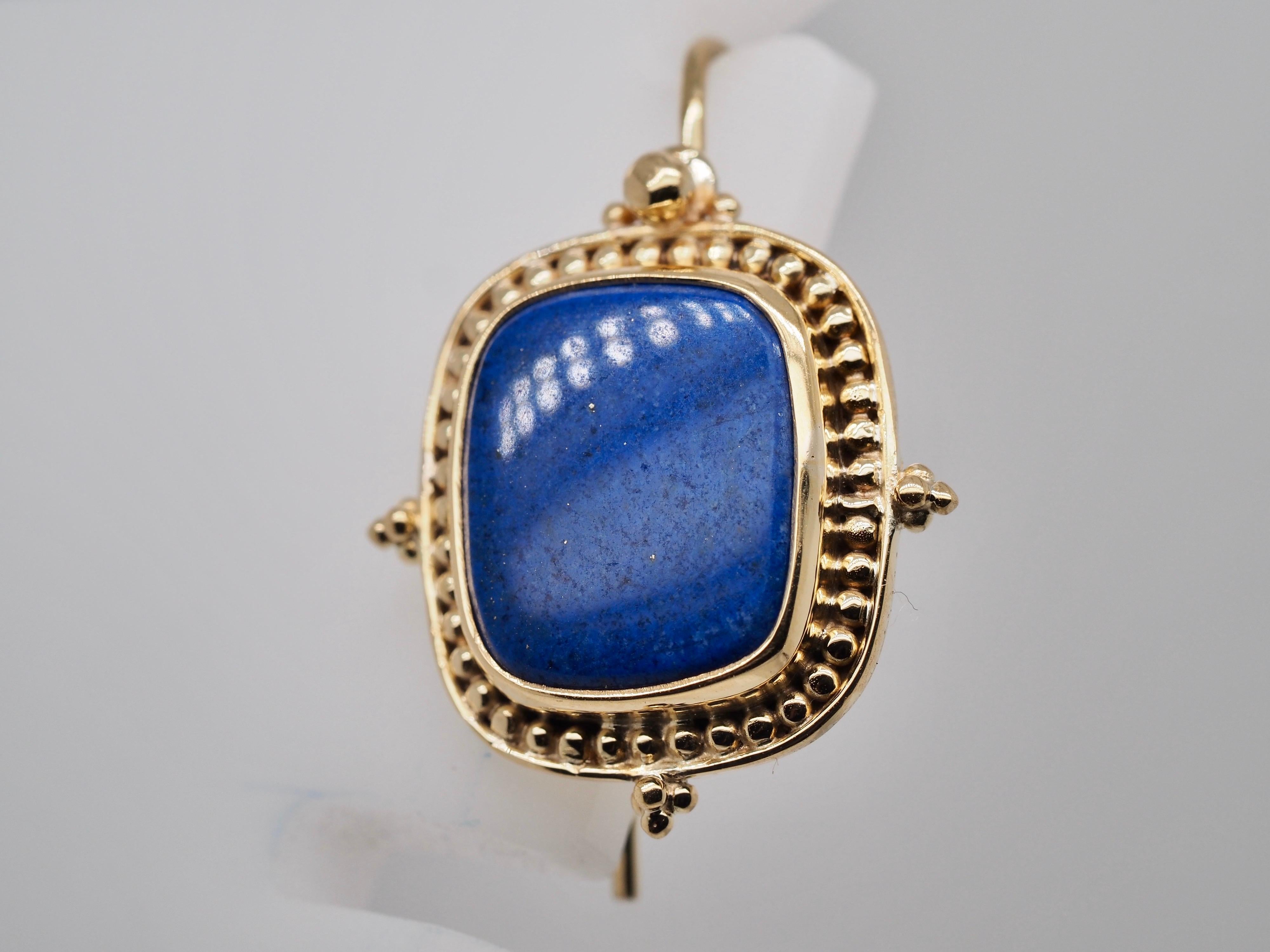 18 Karat yellow gold Lapis Lazuli dangle earrings are perfect for any occasion. The bright royal blue cushion shaped centers are a bright cobalt blue fluttering with golden glitters. The lapis are bezel set in yellow gold with a beaded golden halo