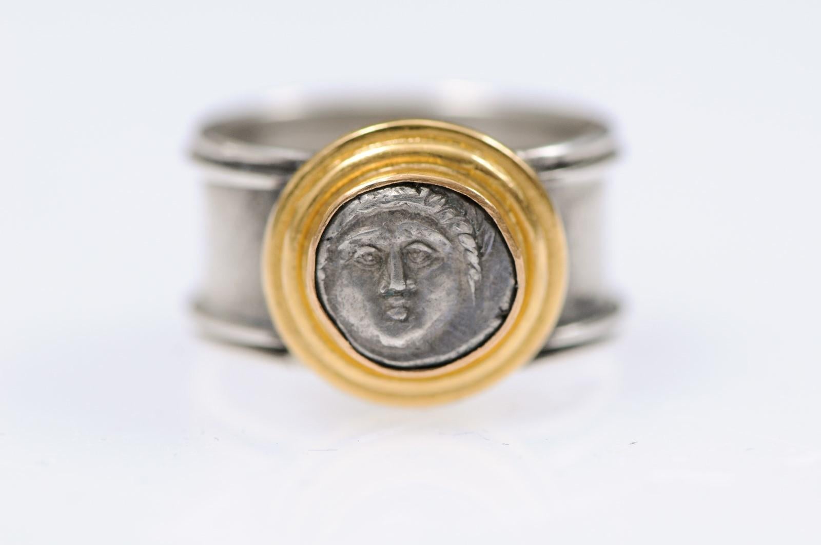 A Greek Diobol silver coin from Apollonia Pontika, from the colony of Milletus on the West Coast of the Black Sea, circa 450-400 BC. This silver Diobol [coin] ring of Apollo trimmed with 22 karat gold is placed on a wide silver band. This coin has