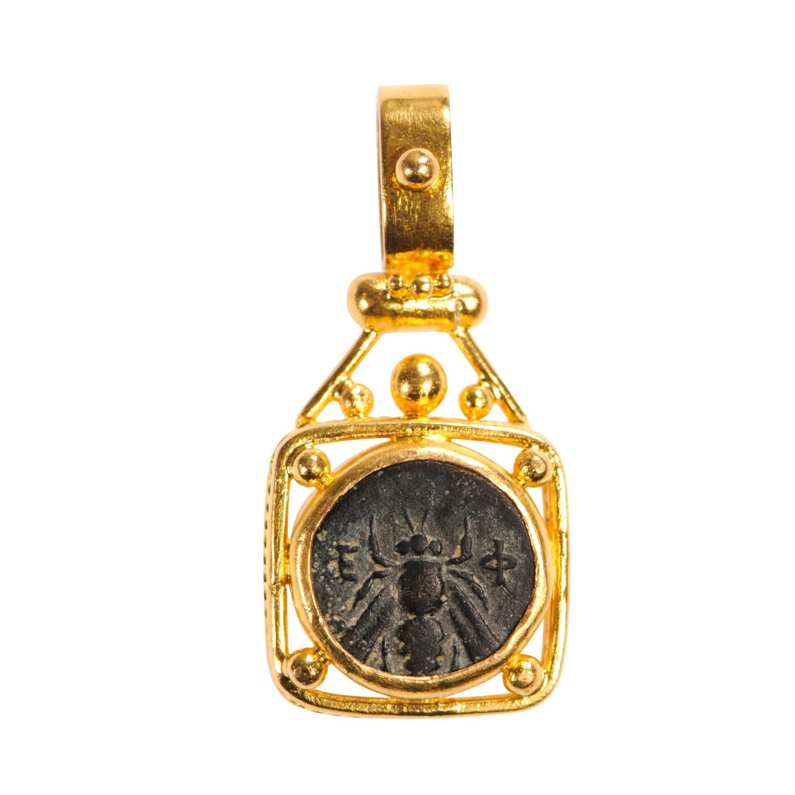 An Authentic Greek Bronze Coin, circa 350 - 300 BC, obverse (front) is a bee with a kneeling stag on reverse, set in a 22k gold squared bezel. The coin pendant measures approximately 1 1/3