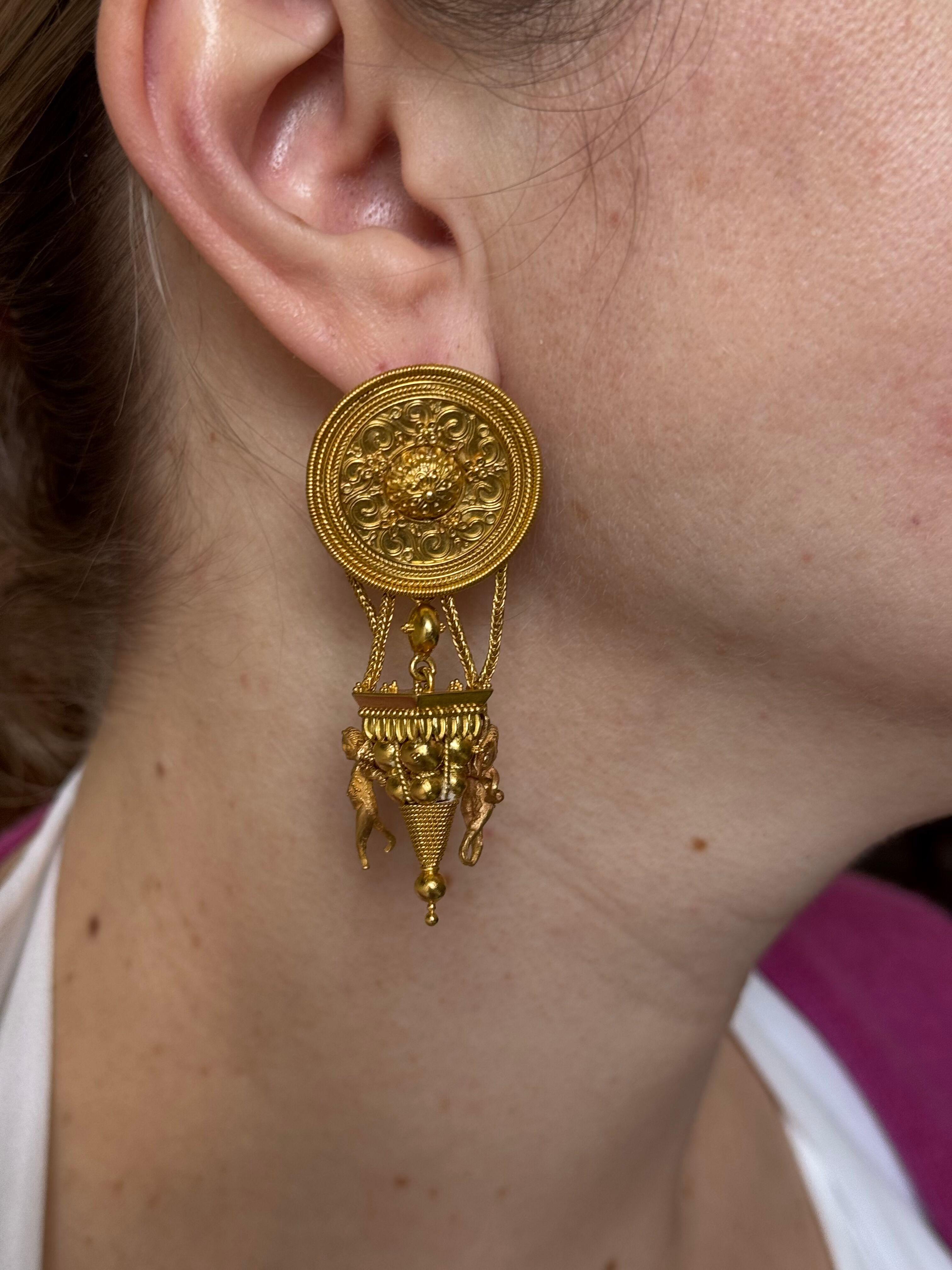 Pair of Greek made Etruscan style earrings, in 18k yellow gold, the earrings feature Cherubs and drop columns. 
Earrings measure 2.5