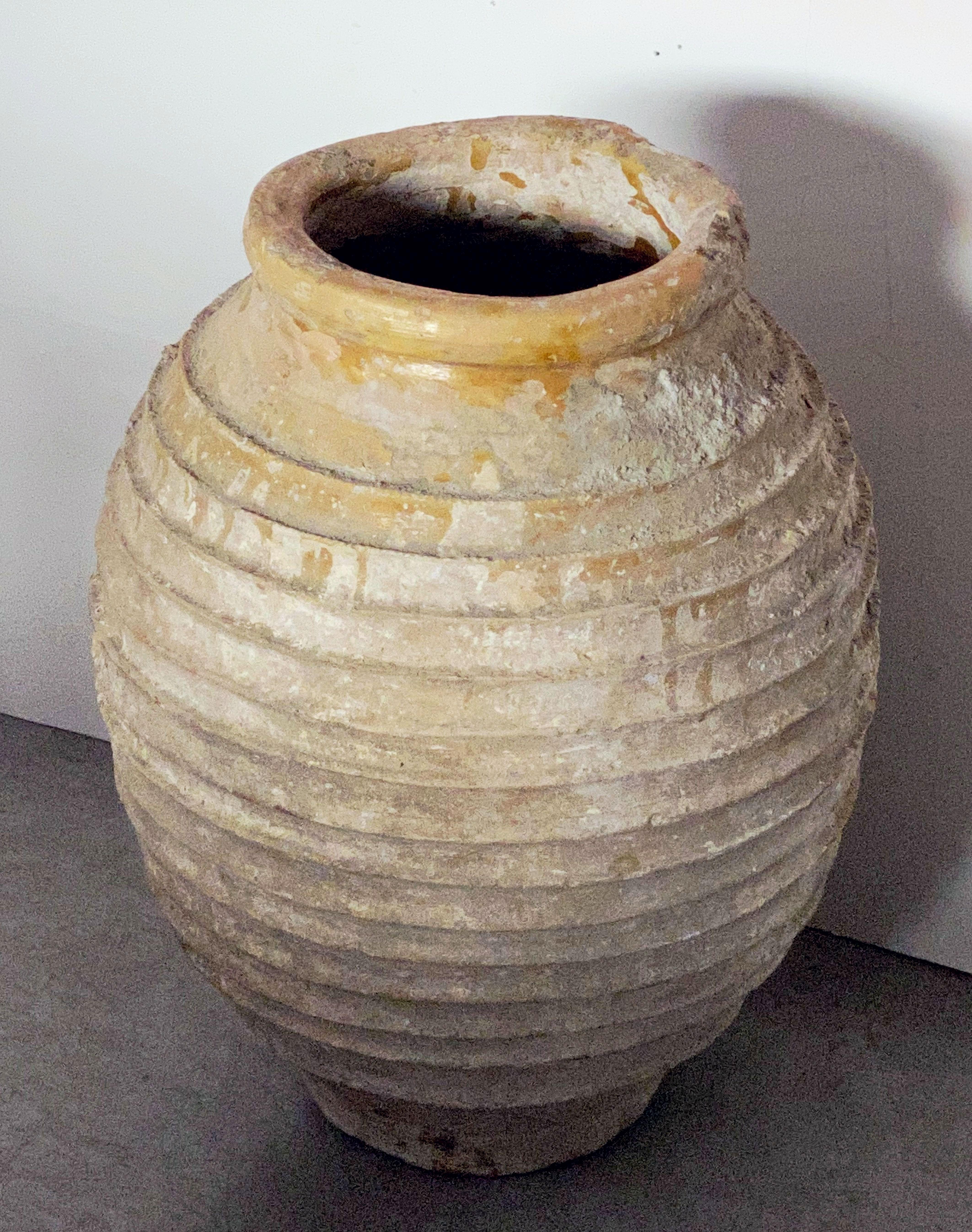 A handsome large Greek garden urn pot (amphora) or oil jar, featuring a glazed top over a ridged, cylindrical body and functional as a garden ornament or planter.

Other similarly-styled jars and pots available.

This pot's dimensions:

Height 23