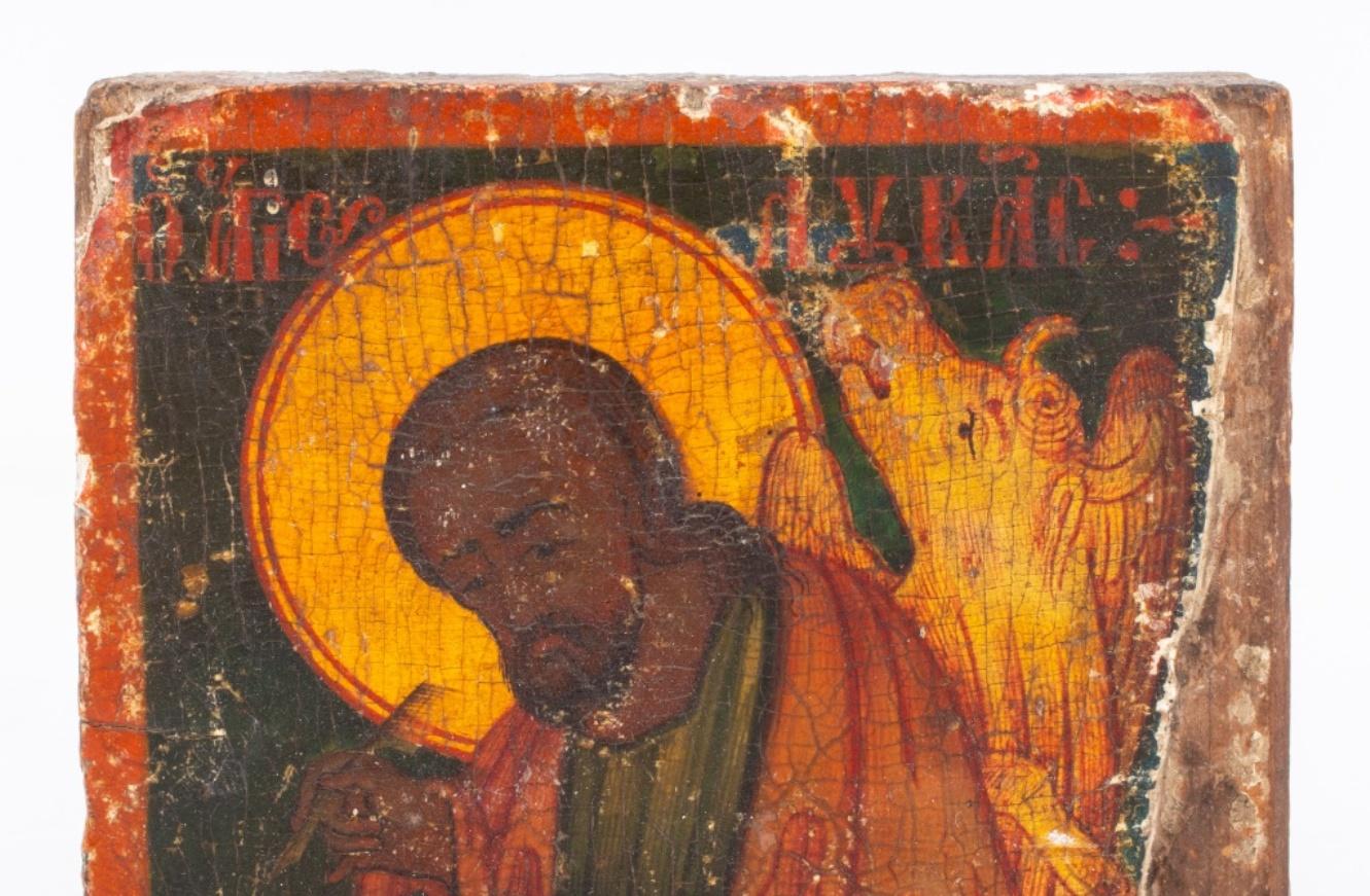 Greek icon of St. Luke the Evangelist, tempera on gesso on wood, depicting the evangelist with his symbol of the winged cow and writing the Gospel (losses), inscribed in Greek 