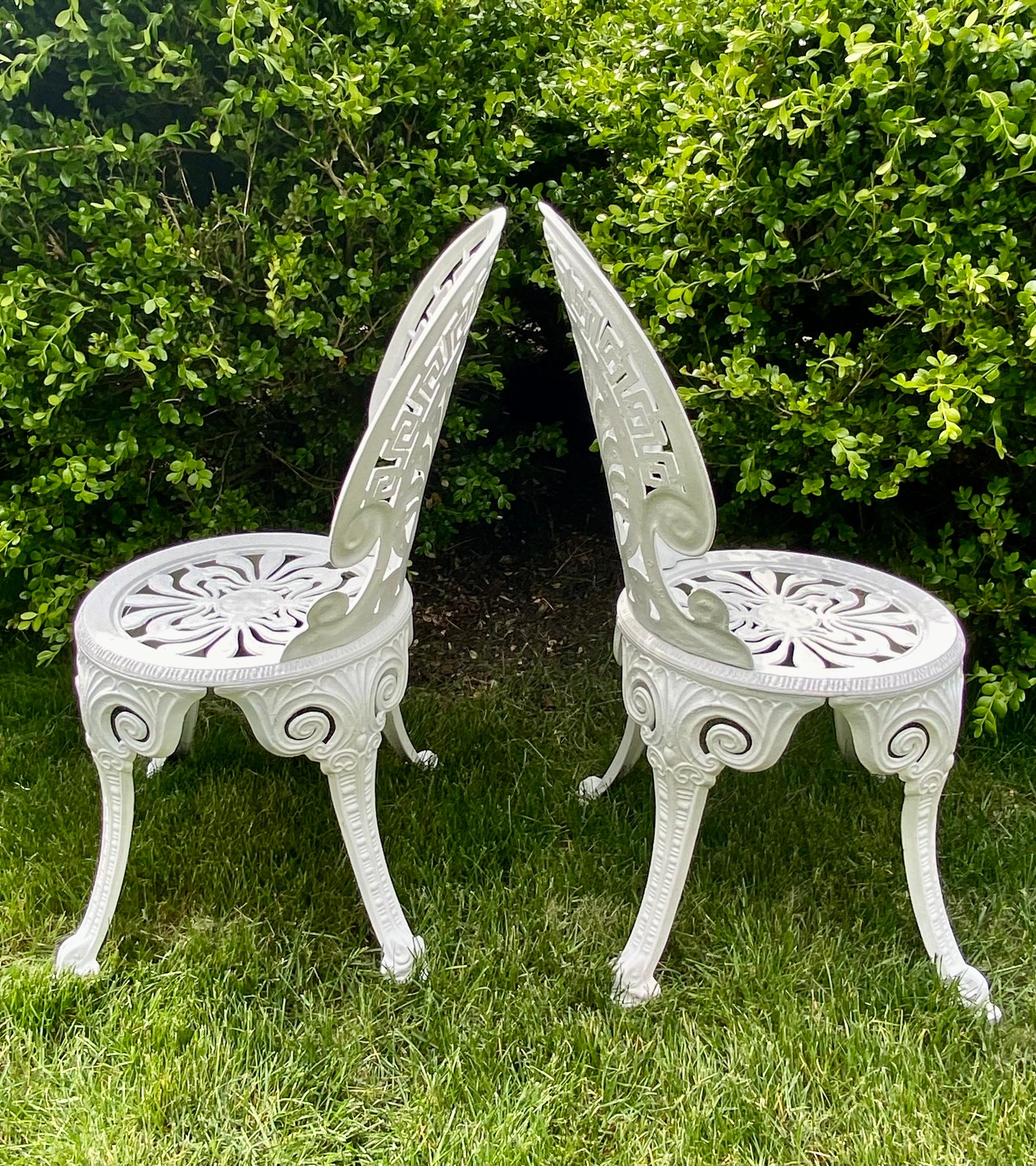 Pair of Hollywood Regency style white aluminum garden chairs with Greek key and fan motifs. These armless side accent chairs are perfect extra seating for the garden or patio. Lightweight, sturdy, and durable.