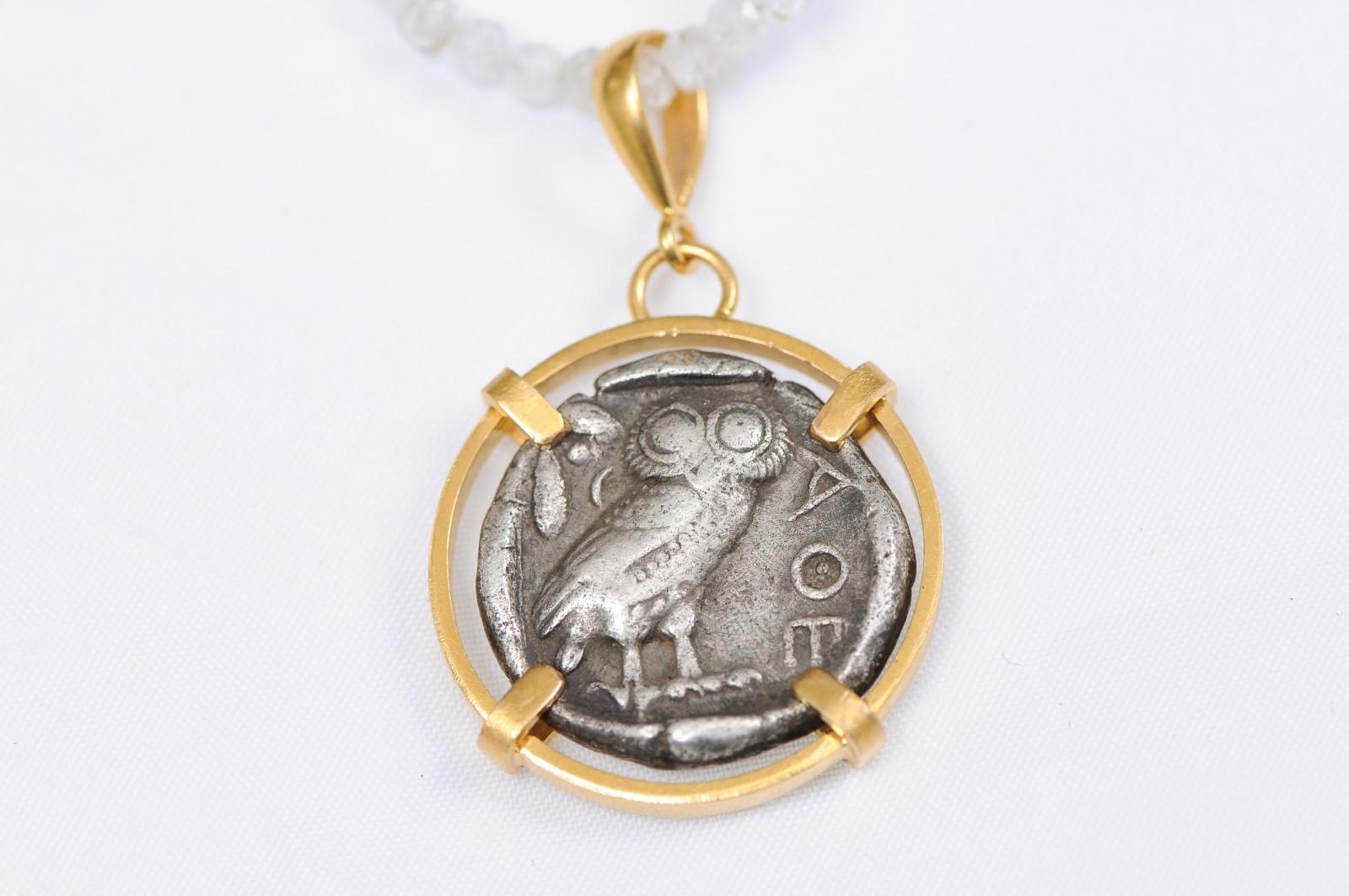 An authentic Greek, Attica, Athens Tetradrachm Owl/Athena coin (circa 430-420 BC), set in a custom rounded, suspended style, 22k gold bezel with 22k gold bail. The obverse, or front side of this coin features the head of Athena, right, wearing a