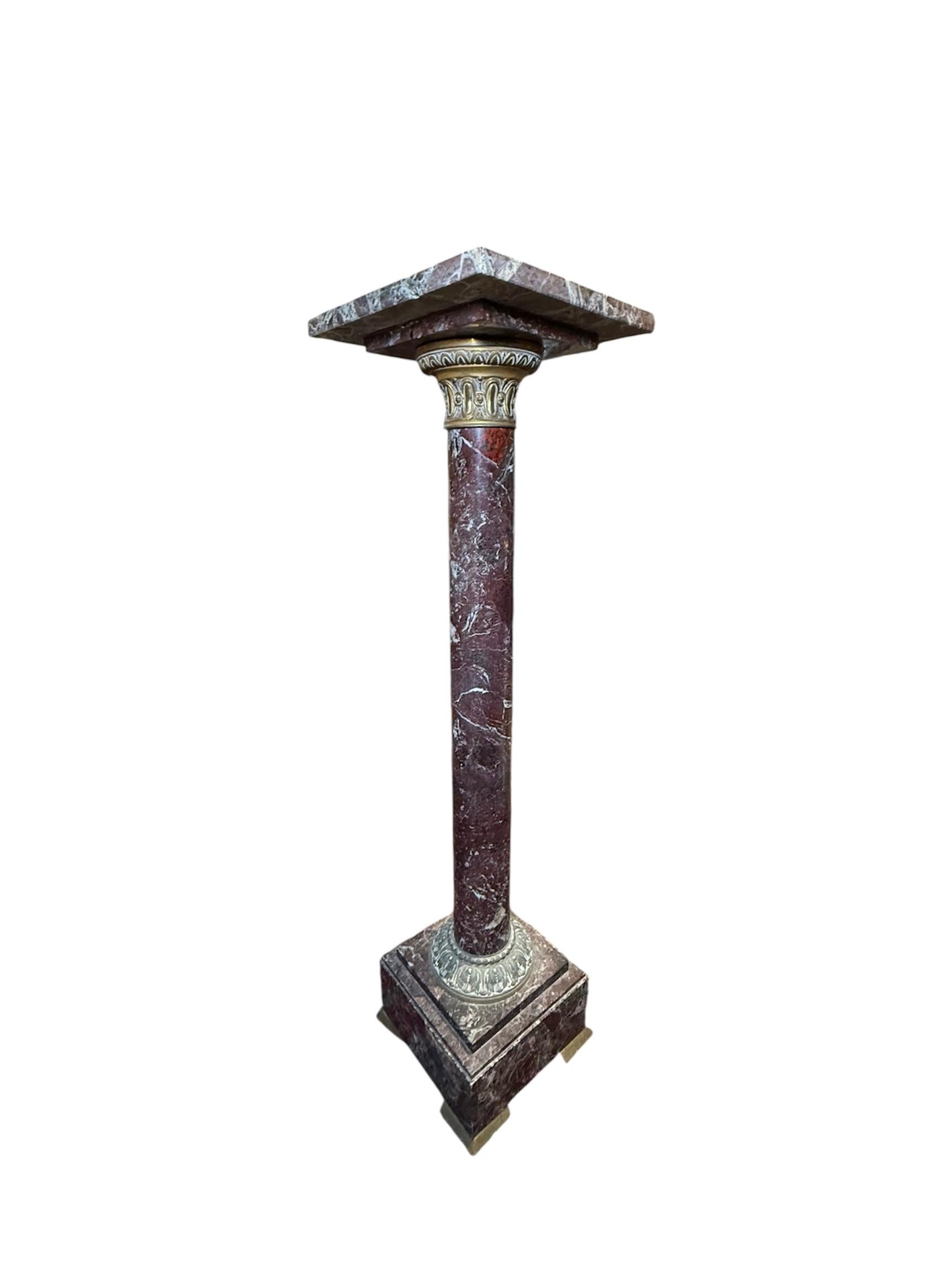 This is a Greek Revival Bronze Marble Pedestal. It depicts a Doric red marble column decorated with a patinated bronze wide band adorned with an egg and dart pattern at the upper part and beads/leaves pattern at the bottom part of it. Two squared