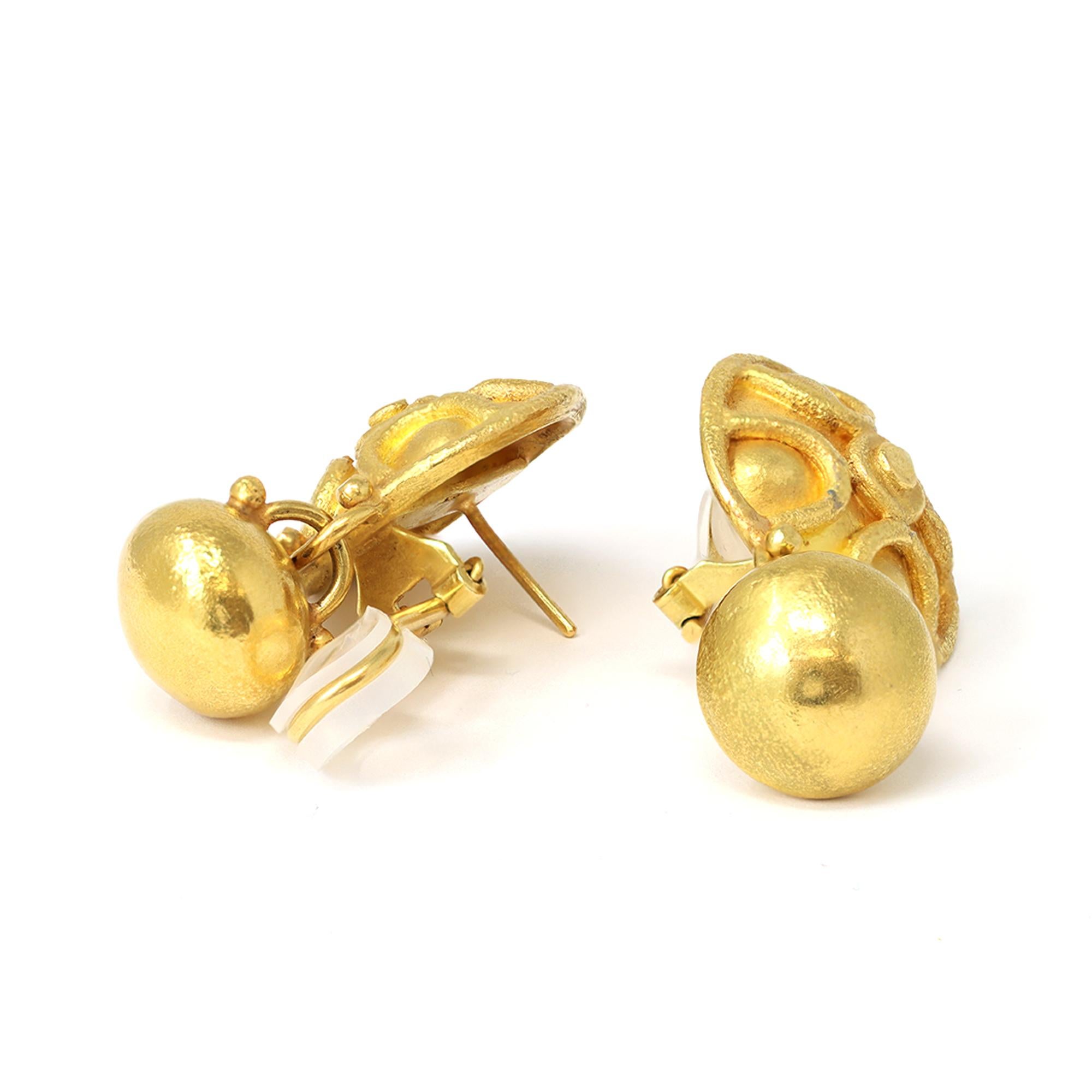 Die auffälligen Ohrringe aus hochkarätigem Gold weisen ein schildförmiges Design auf, das von antiken griechisch-römischen Motiven inspiriert ist. Sie endet unten mit einer unförmigen, baumelnden Kugel. Die handgefertigten italienischen