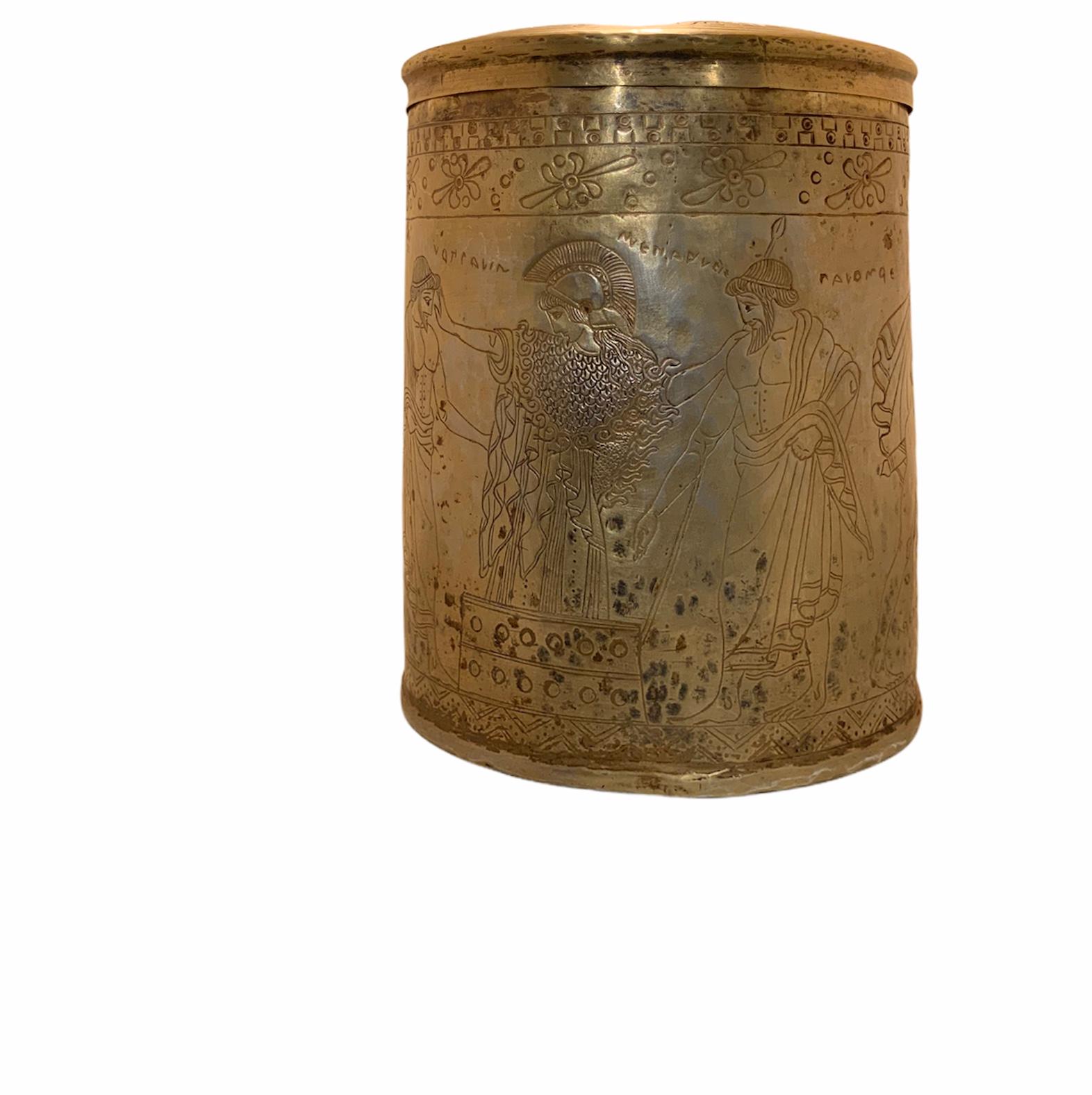 This is a Greek style engraved and chased gold tone metal large Pyxis ( a cylindrical vessel/box with a lid that can be made of wood, ivory or metal). In the ancient times, it was mostly used by women to storage and transport trinkets, jewelry and