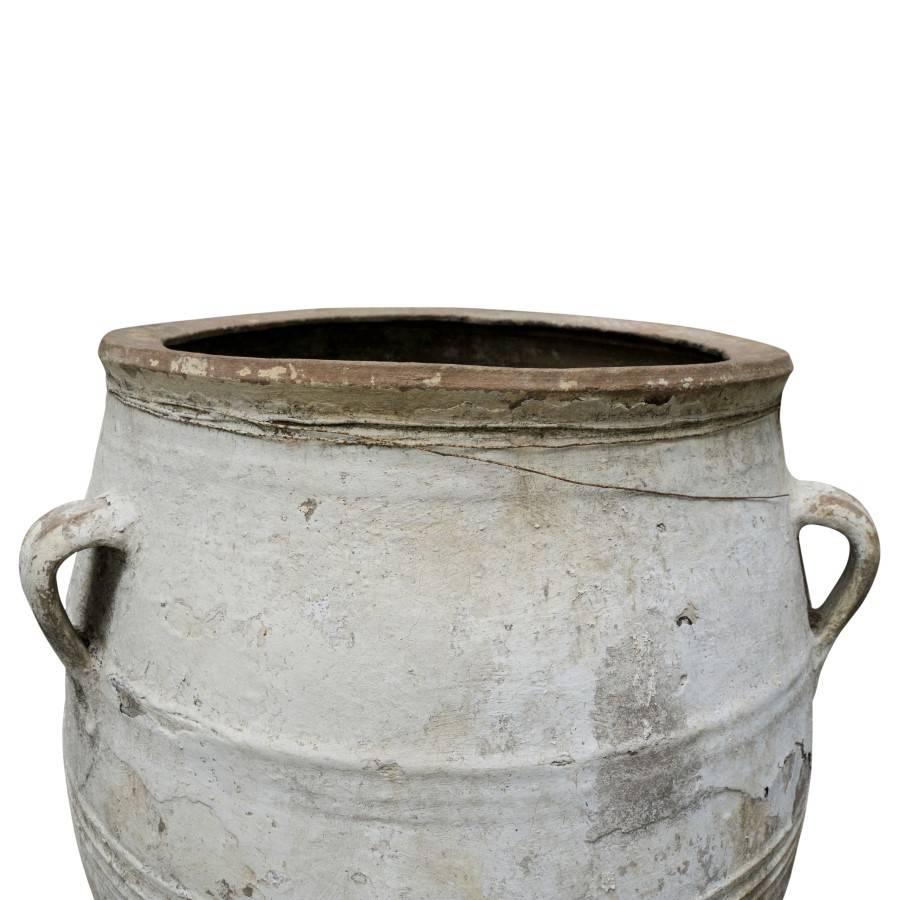 This is a large terracotta urn standing 41 inches tall, fitting for an antique themed exterior landscape or open space interiors. Coated in white paint and textured shades of patina this Greek urn adds a timeless elegance for use as decoration or
