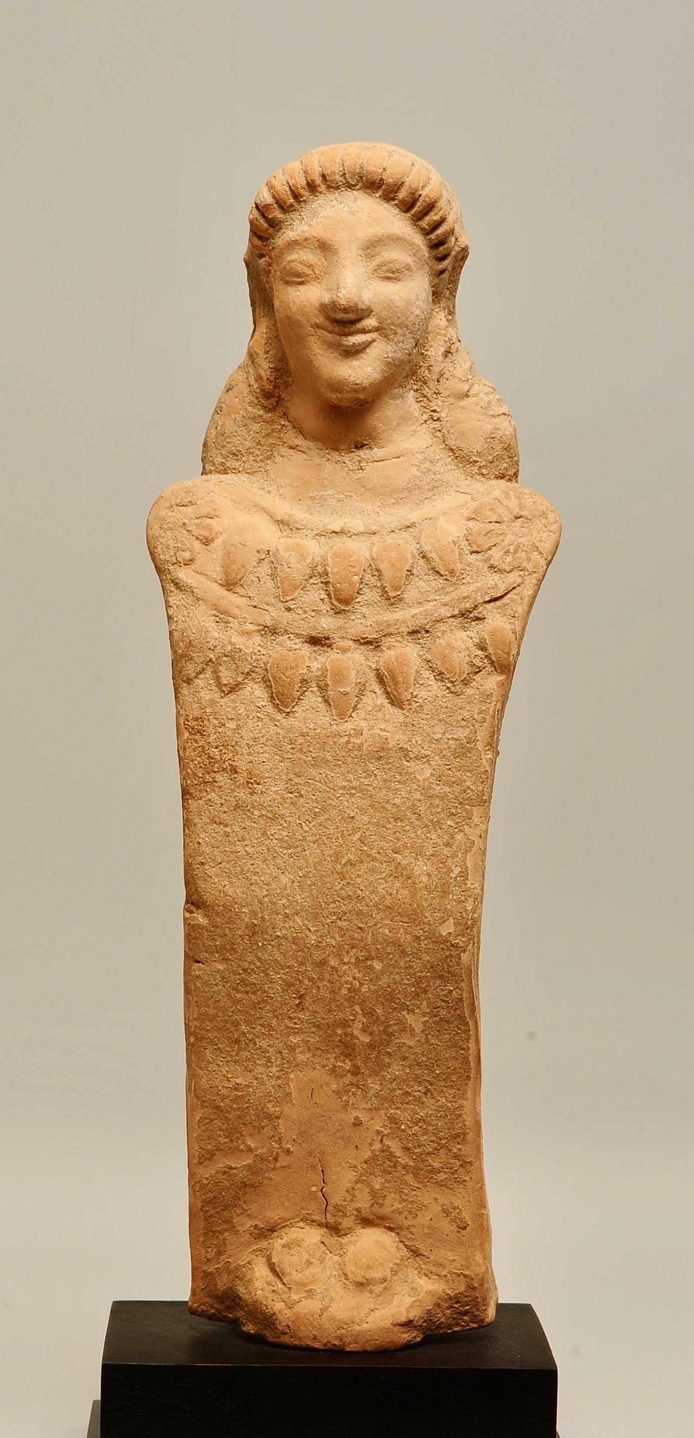 Griechische Terrakotta-Votivfigur einer Göttin, wahrscheinlich Demeter oder Kore, die eine große Zwillingskette mit eiförmigen Früchten (Eicheln?) trägt, mit einer Rosette auf jeder Schulter. Westgriechisch, Sizilien (?), spätes 6. Jahrhundert v.