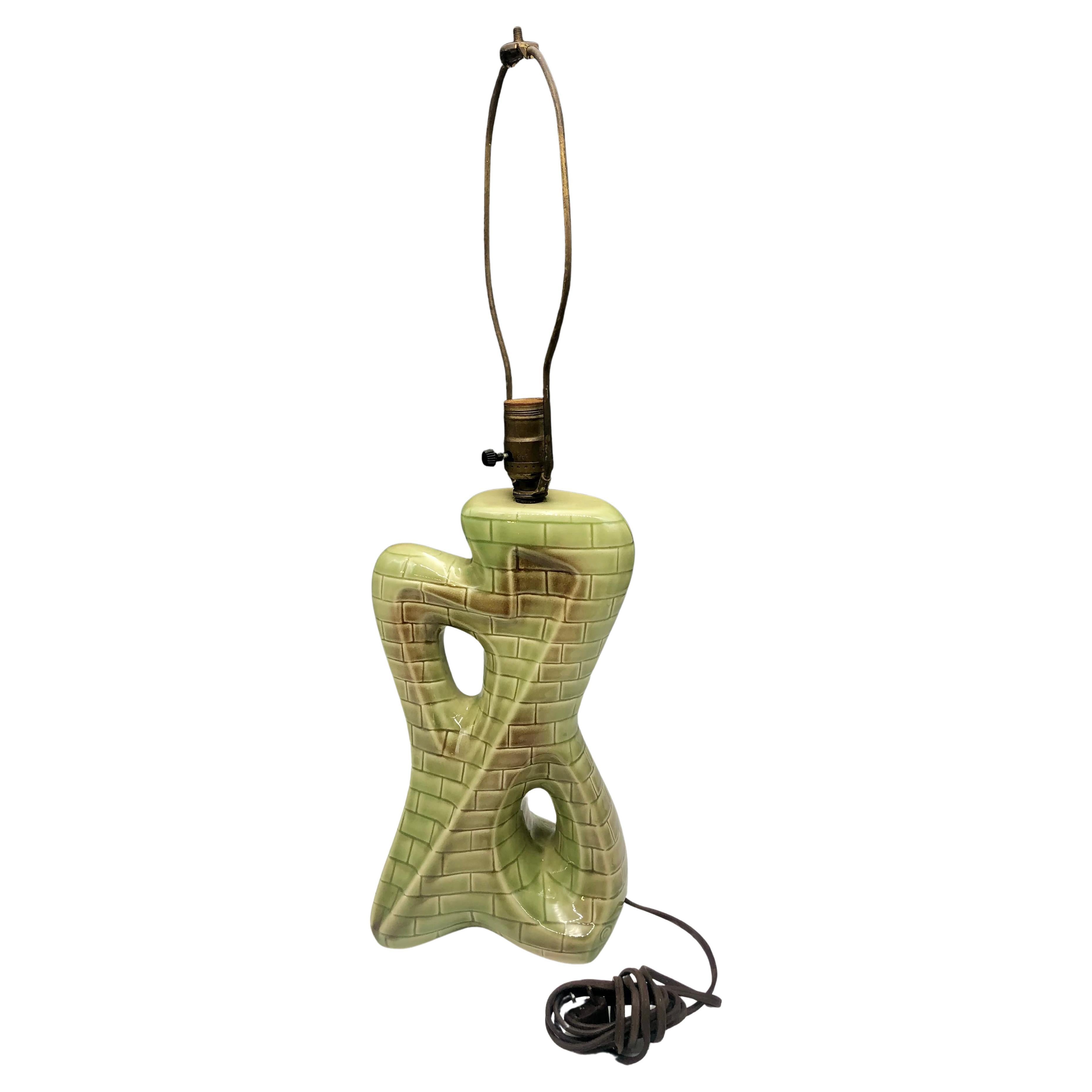 Questa sorprendente lampada da tavolo in ceramica della metà del secolo scorso incarna l'audace spirito artistico degli anni '50-'60, fondendo la forma scultorea con il design giocoso della superficie. Il corpo è caratterizzato da una silhouette