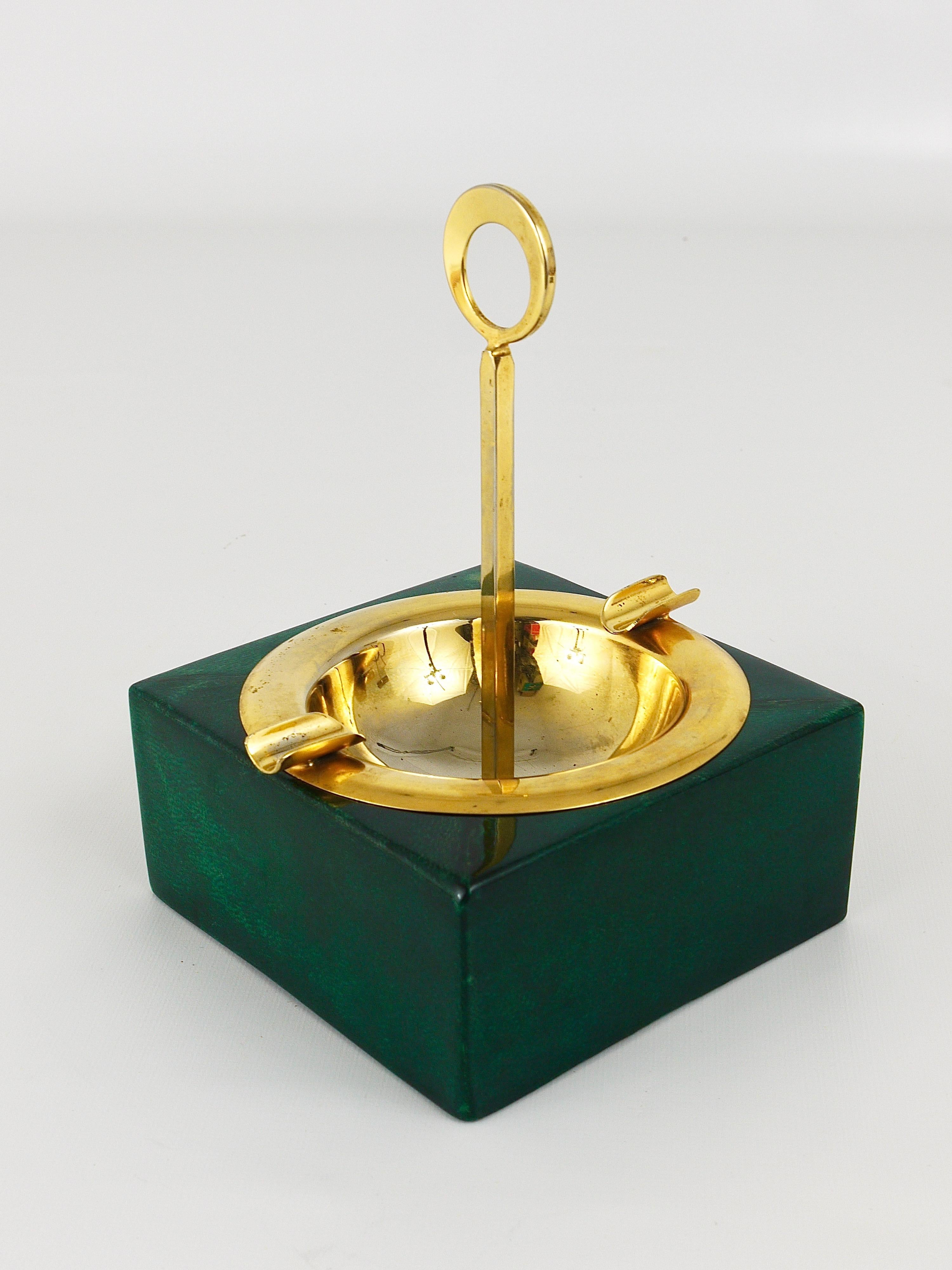 A beautiful modernist ashtray from the 1970s by Aldo Tura, Milano. It has a square wooden base with lacquered green colored goatskin parchment veneer and a gilt metal inlay and handle. In good condition with nice patina.