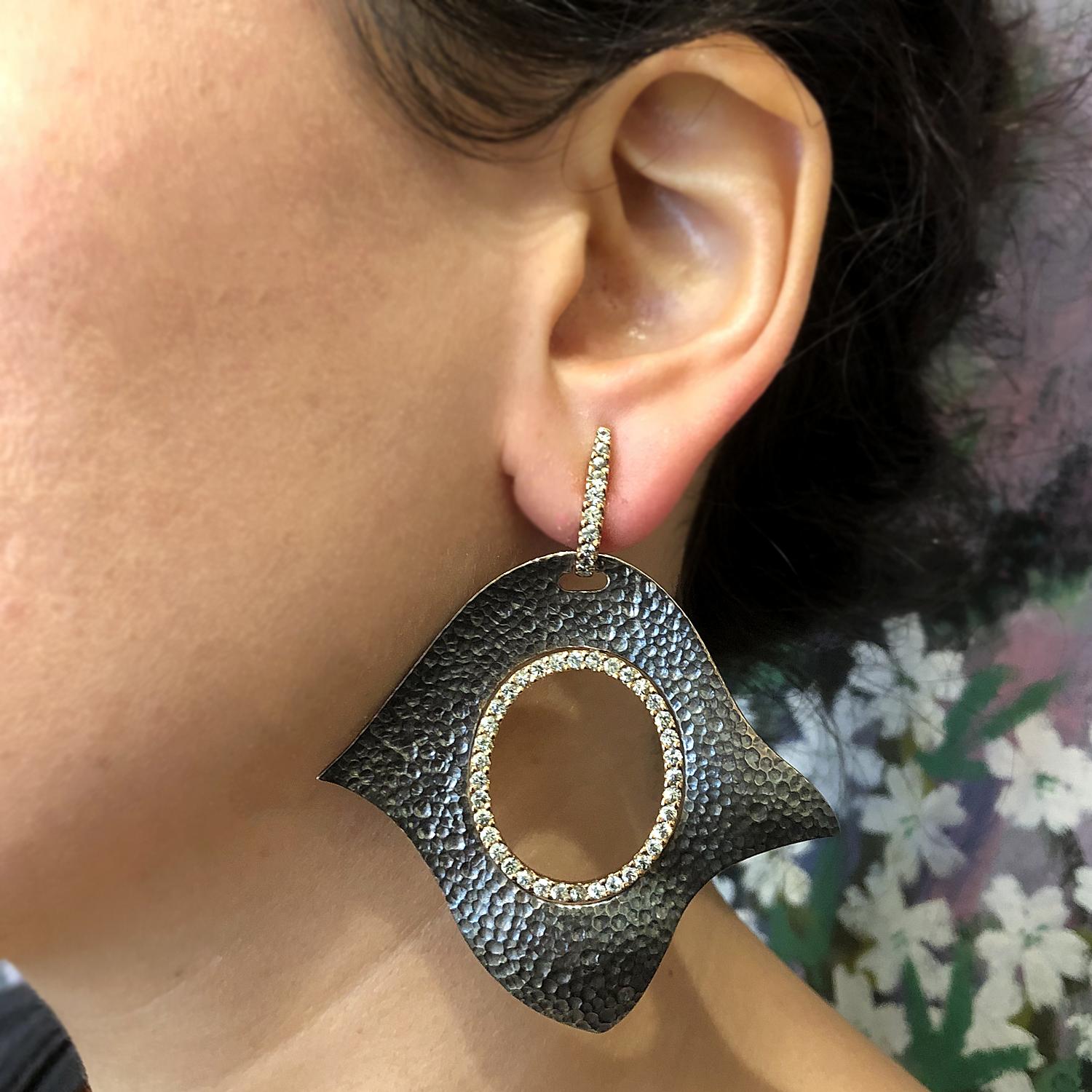 A designer pair of earrings which incorporates both 18K rose gold and textured silver with a hammered finish. Round green amethyst is set on the 18K rose gold giving the earrings sparkle and life.

Dimensions: 2.75 x 1.35 inches 
