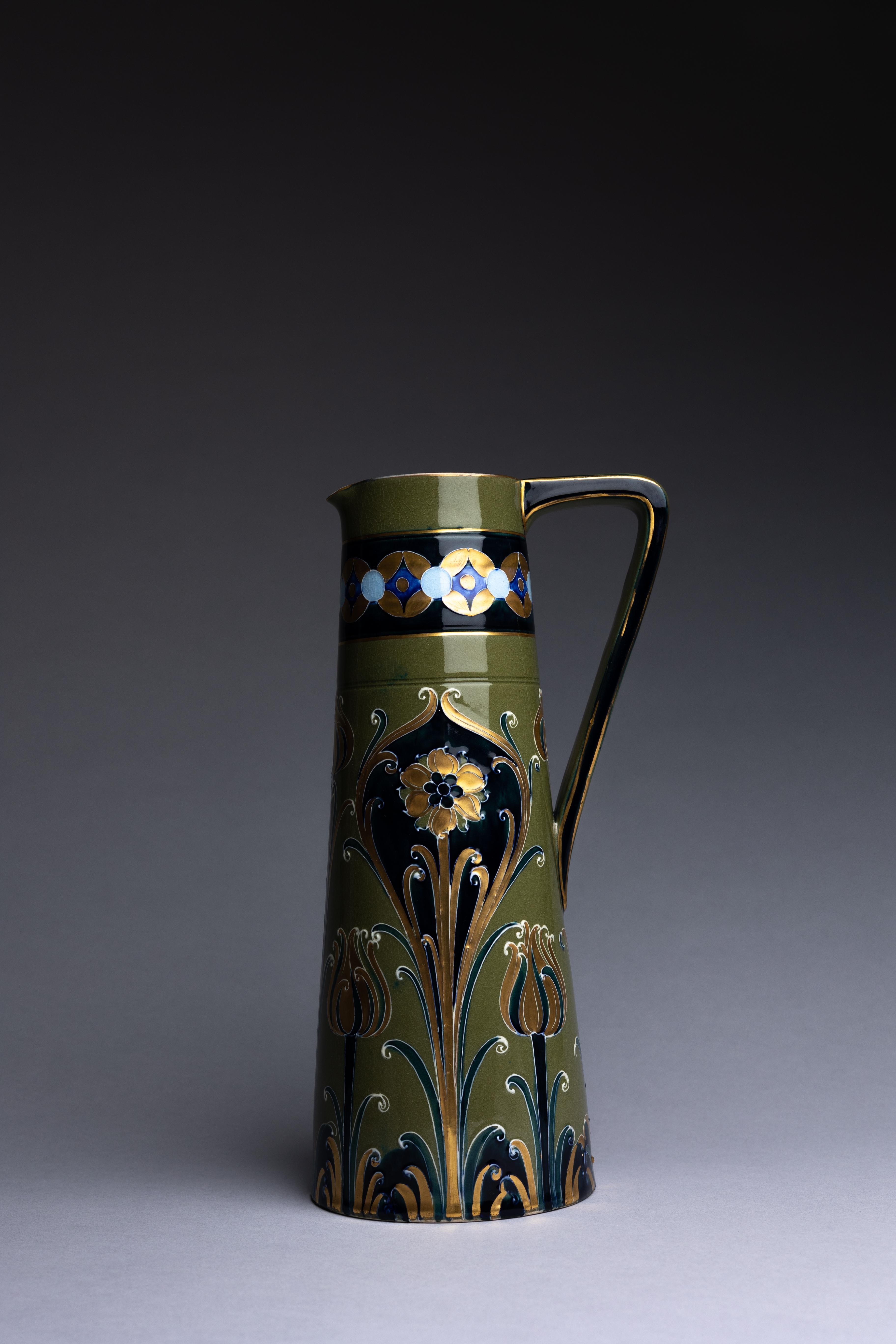 A decorative pottery pitcher created by William Moorcroft for James MacIntyre & Co. in 1903.

This pitcher is part of William Moorcroft's Green and Gold Florian line. In producing these wares, Moorcroft utilized a medieval ceramic technique of