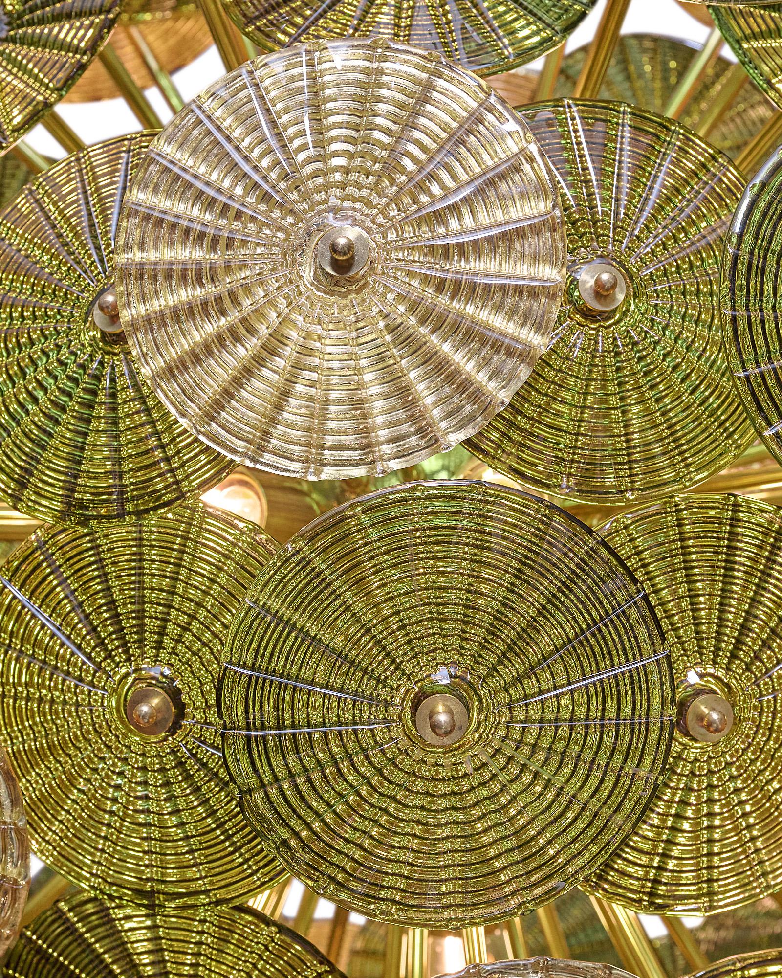 An Italian Murano glass sputnik chandelier with gold and green glass elements. This fixture has layered circular glass pieces; each hand-blown using the “stampato” technique. They alternate between a striking olive green and a gold leafed finish. We