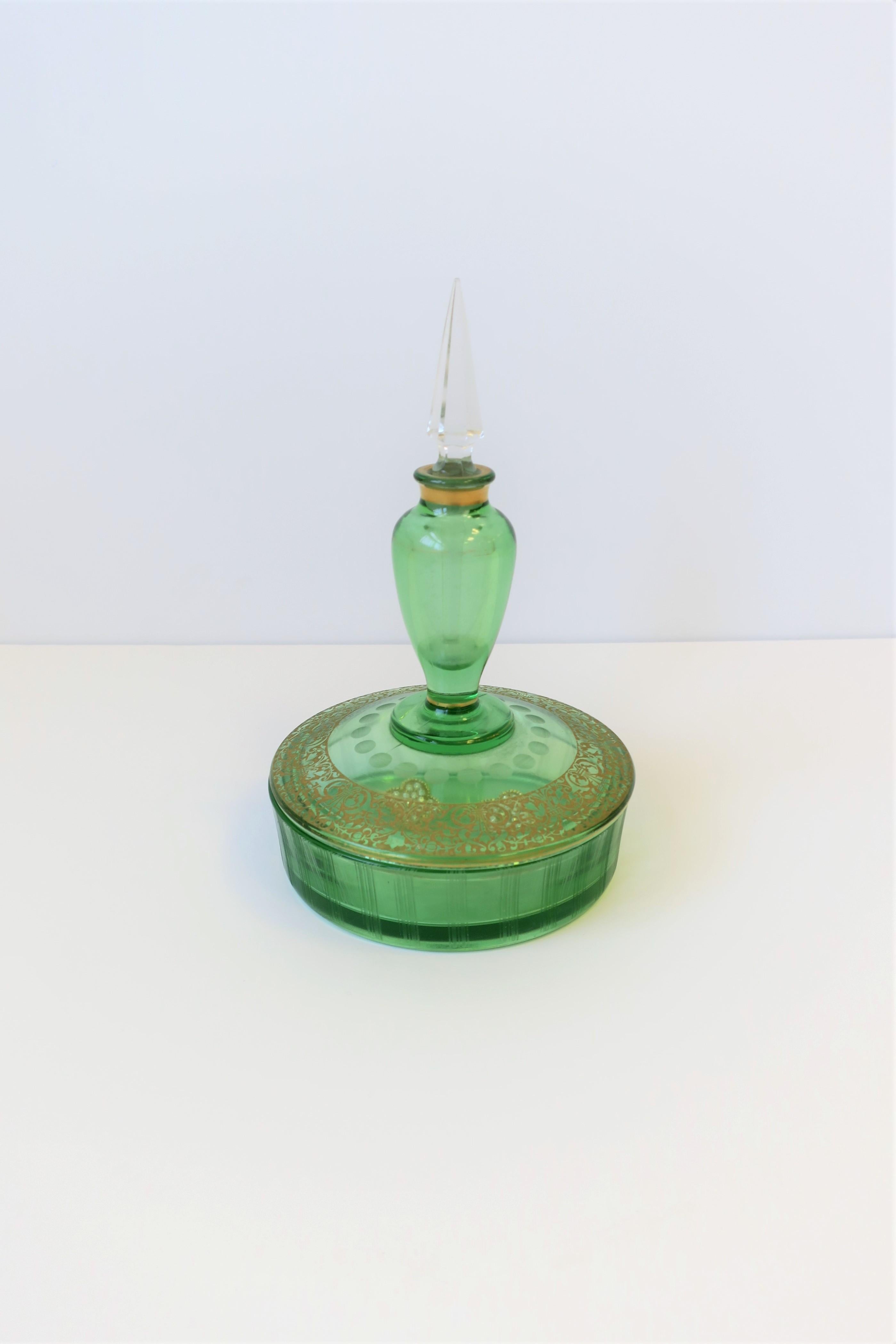 A green glass and gold gilt round jewelry box and perfume vanity bottle, circa early to mid-20th century. This is a unique piece; a box and perfume bottle in one. A great piece for a vanity, bath, nightstand area, etc. Dimensions: 6