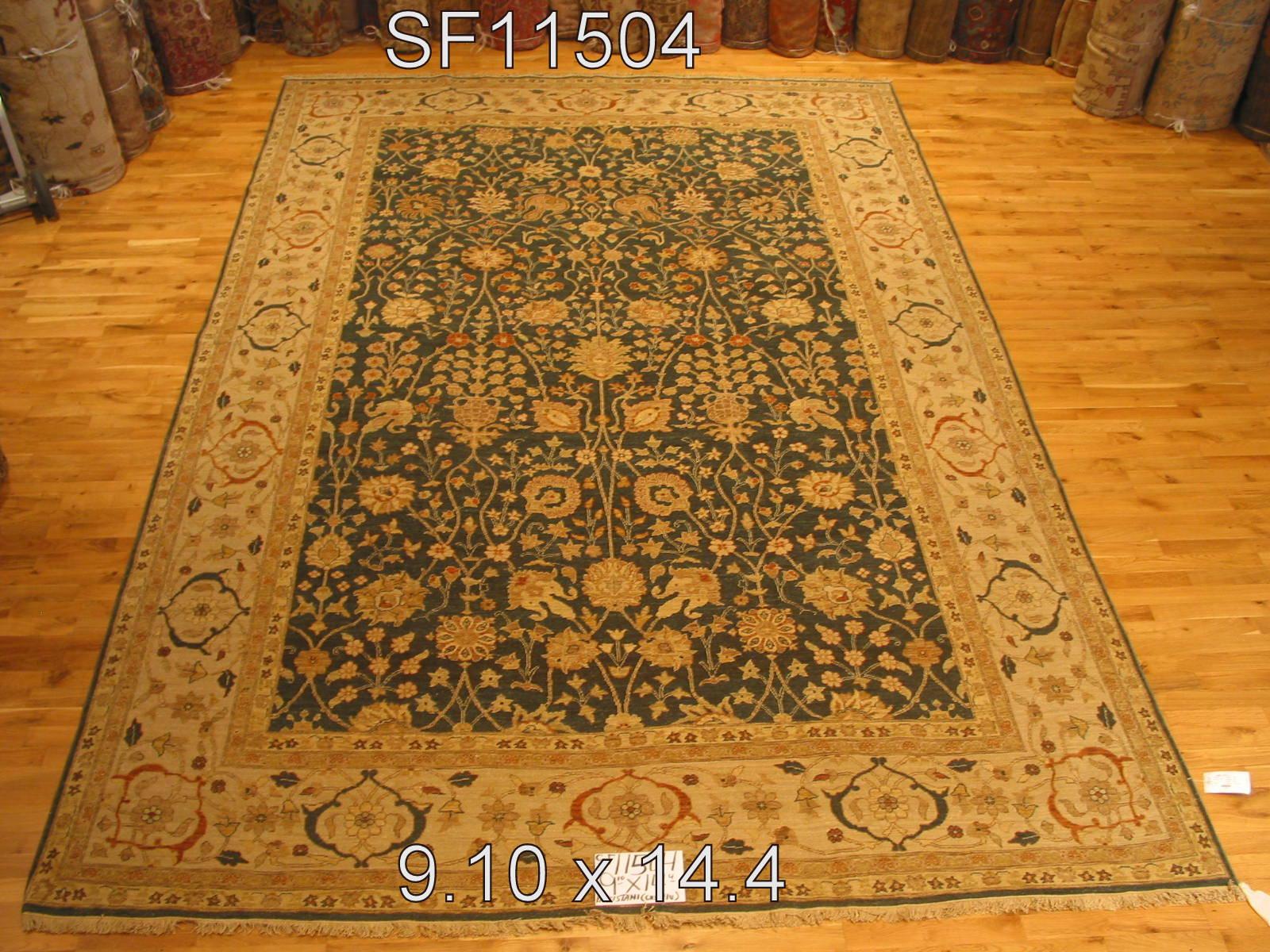 Bring the blooming garden indoors with this unusual traditional style wool area rug that will be equally at home in formal and informal settings. Dark forest green center panel and ivory border with beige, rust, taupe and yellow/gold elements. Hand