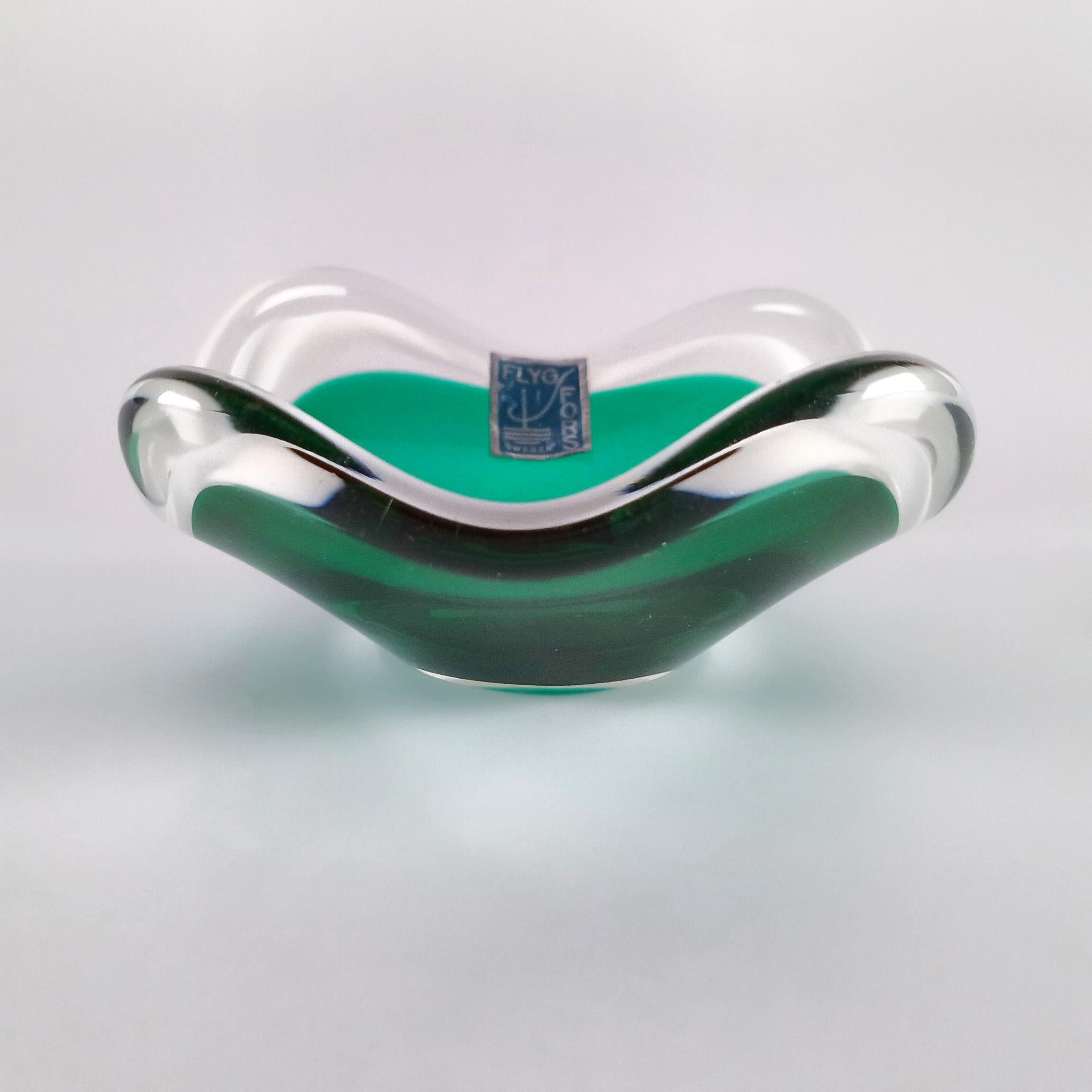 Un affascinante esempio di art glass svedese della metà del secolo, questa piccola ciotola Coquille è stata disegnata da Paul Kedelv per Flygsfors Glasbruk ed è datata 1953. Il pezzo appartiene all'iconica serie Coquille, che prende il nome dalla