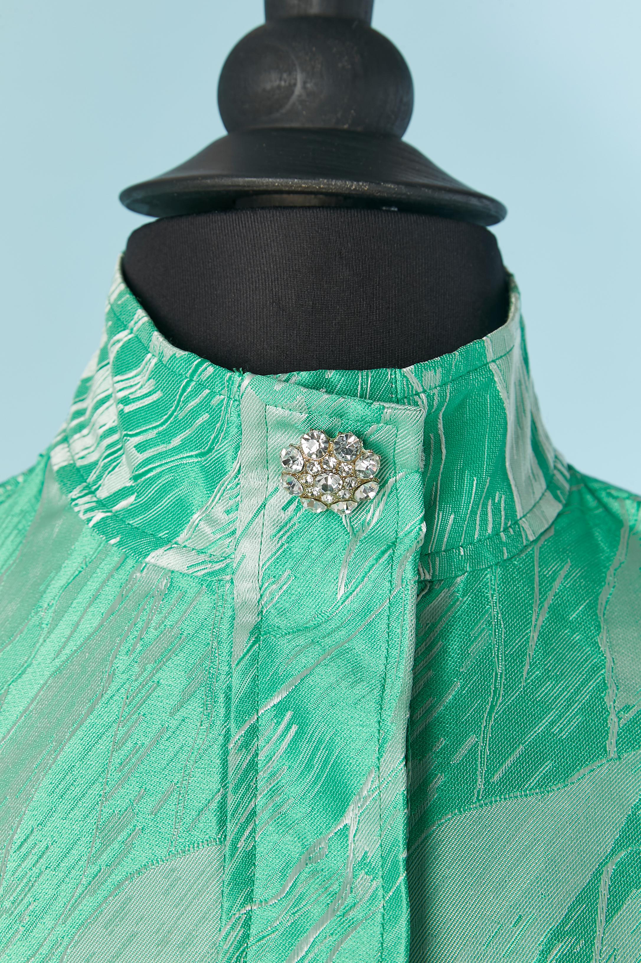 Grünes und weißes Jacquard-Cocktailkleid. Zusammensetzung des Stoffes: 100% Polyester. 
Verdeckter Druckknopfverschluss in der vorderen Mitte. Dekorativer Strassknopf auf der oberen mittleren Vorderseite. Elastisches Band an der Unterseite des