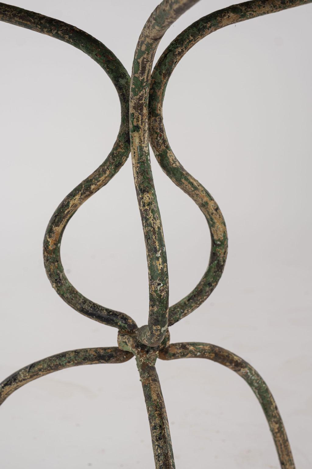 Green and white painted iron garden table designed with a pierced round top raised upon delicate, shapely tripod legs.