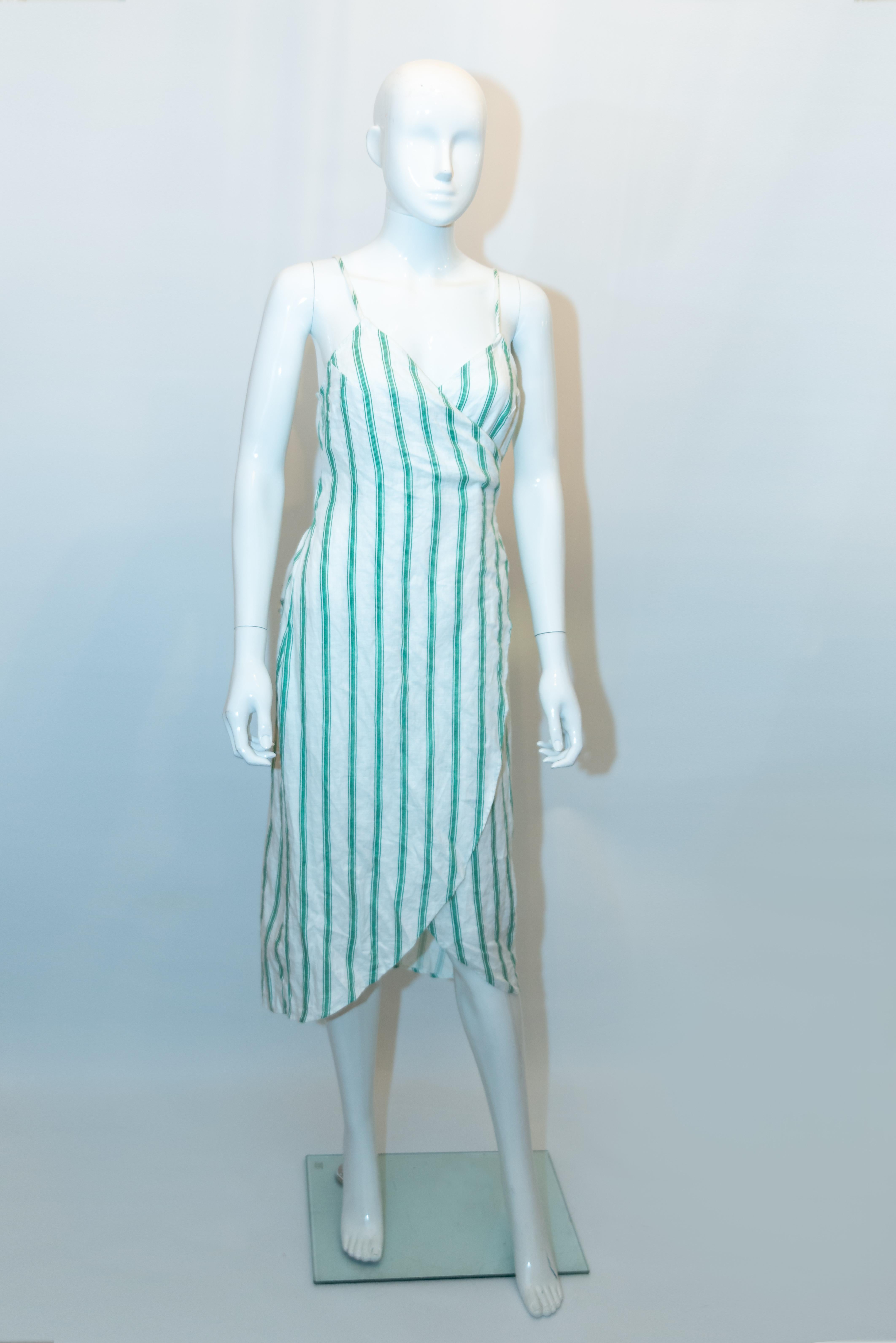 Un elegante vestido de lino a rayas de Reformation.  El vestido es de una alegre raya verde y blanca, con tirantes de espagueti y un lazo en la parte delantera. Medidas : Busto hasta 36'', largo 46''