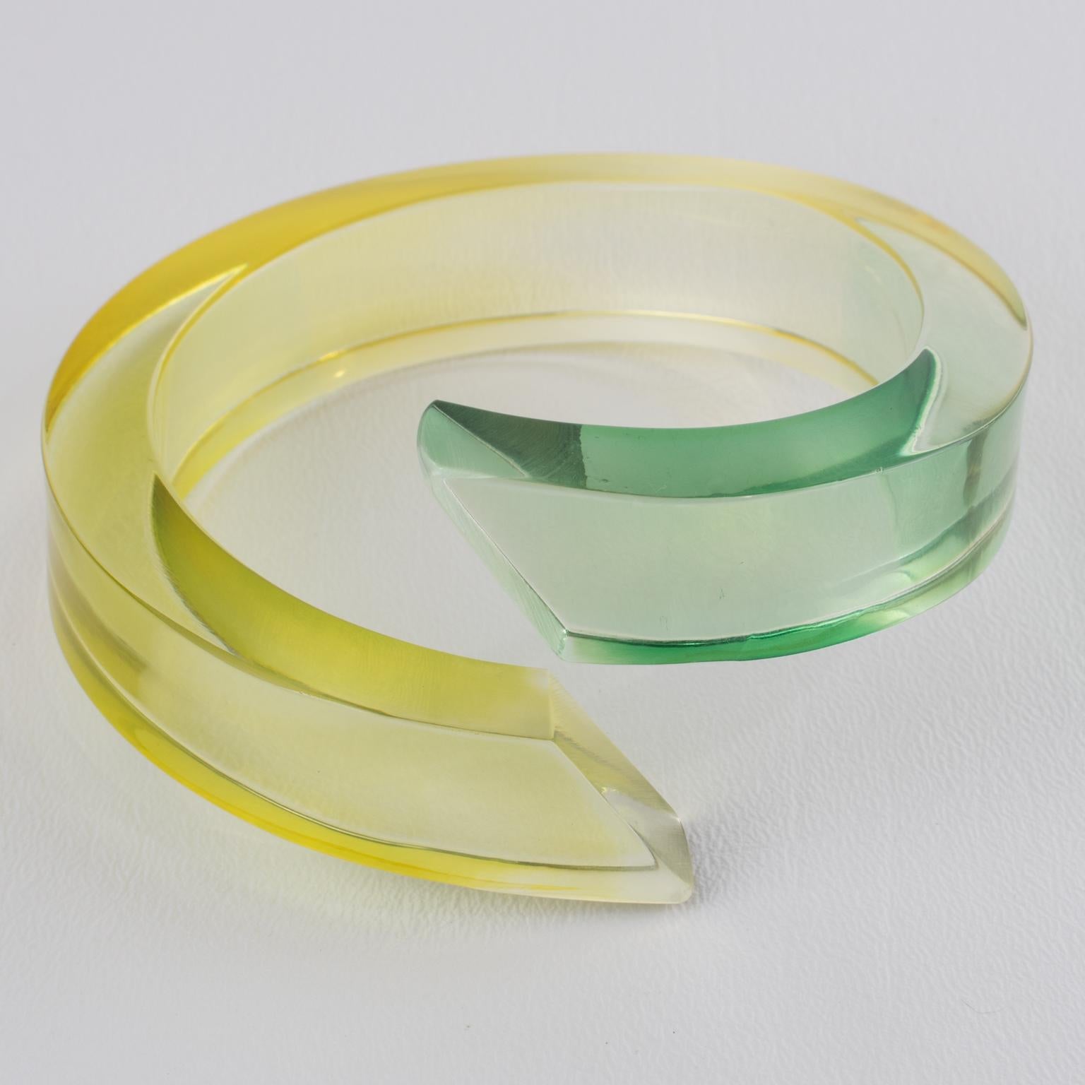 Este asombroso brazalete escultórico de Lucite de la Era Espacial de los años 80 tiene una gruesa forma enrollada y envuelta, hecha a mano, de color mayoritariamente transparente y terminaciones en colores verde almendra y amarillo cítrico. No hay