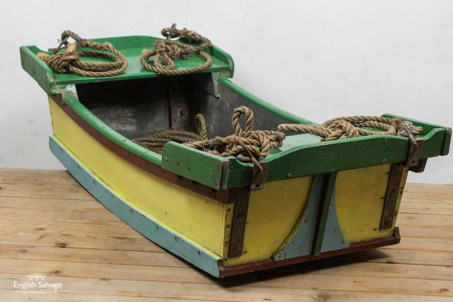 A handmade, wooden boat with rope attached, by iron fittings, to all four corners. As shown in the photographs this boat shows a great deal of wear with the flaking paint and well worn ropes. Warning - this boat may not float!