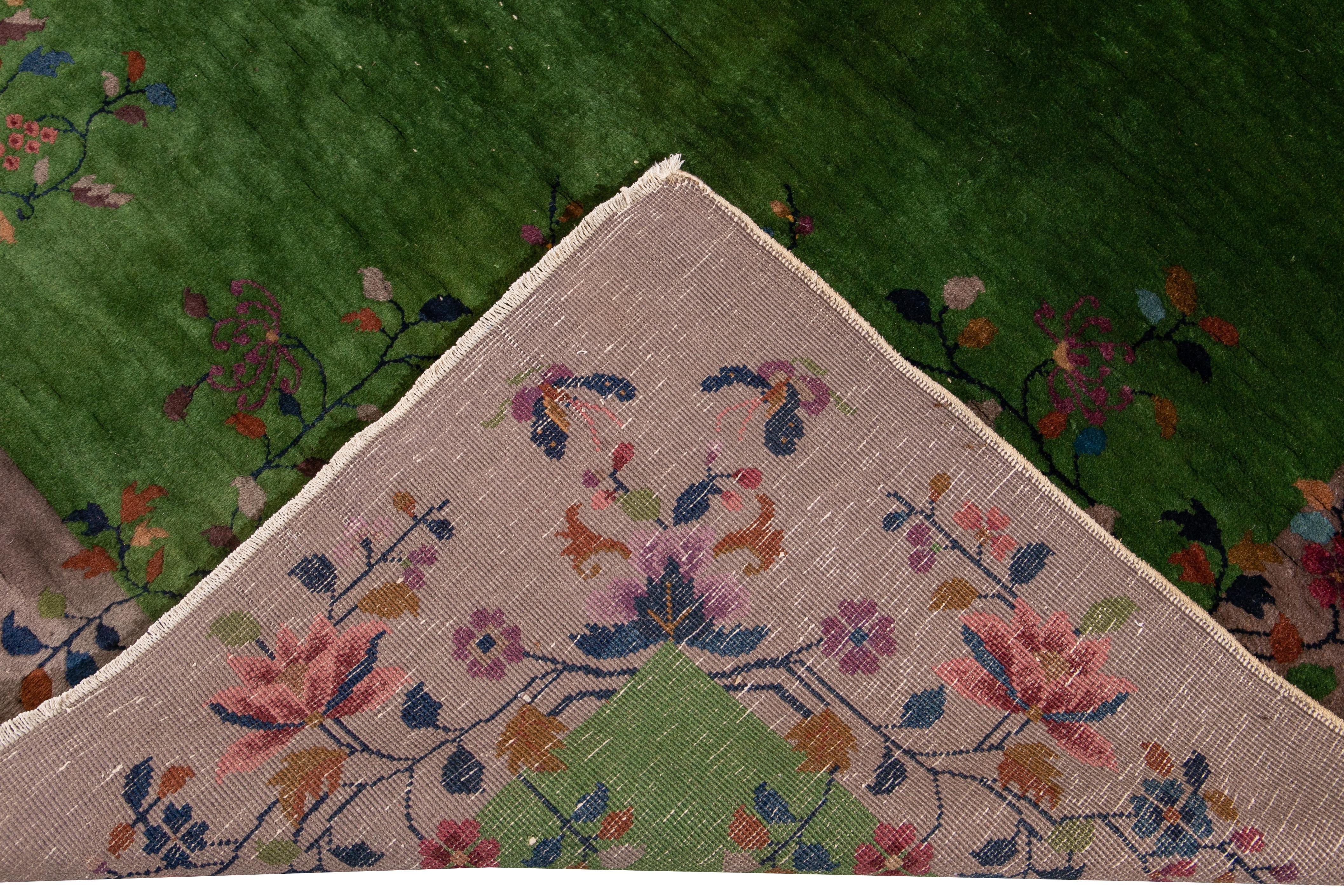 A beautiful antique Art Deco Chinese hand knotted wool rug with green field. This rug has a frame of purple and multi-color accents in a gorgeous all-over Chinese floral design. 

This rug measures: 9' x 11'10