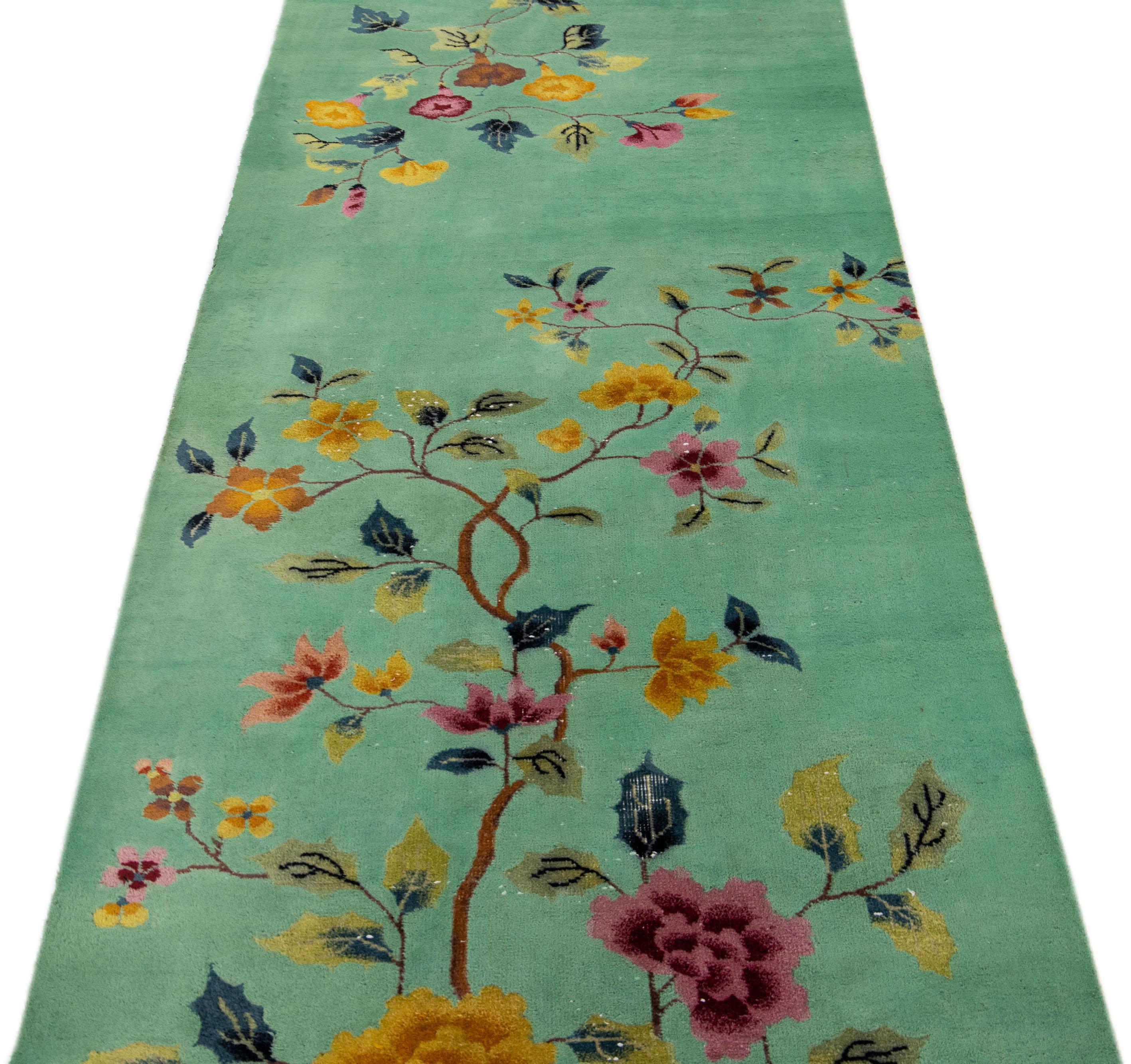 Beautiful antique Art Deco hand-knotted wool rug with a green field. This piece has multi-color accents in a gorgeous traditional Chinese floral design. 

This rug measures: 3'1